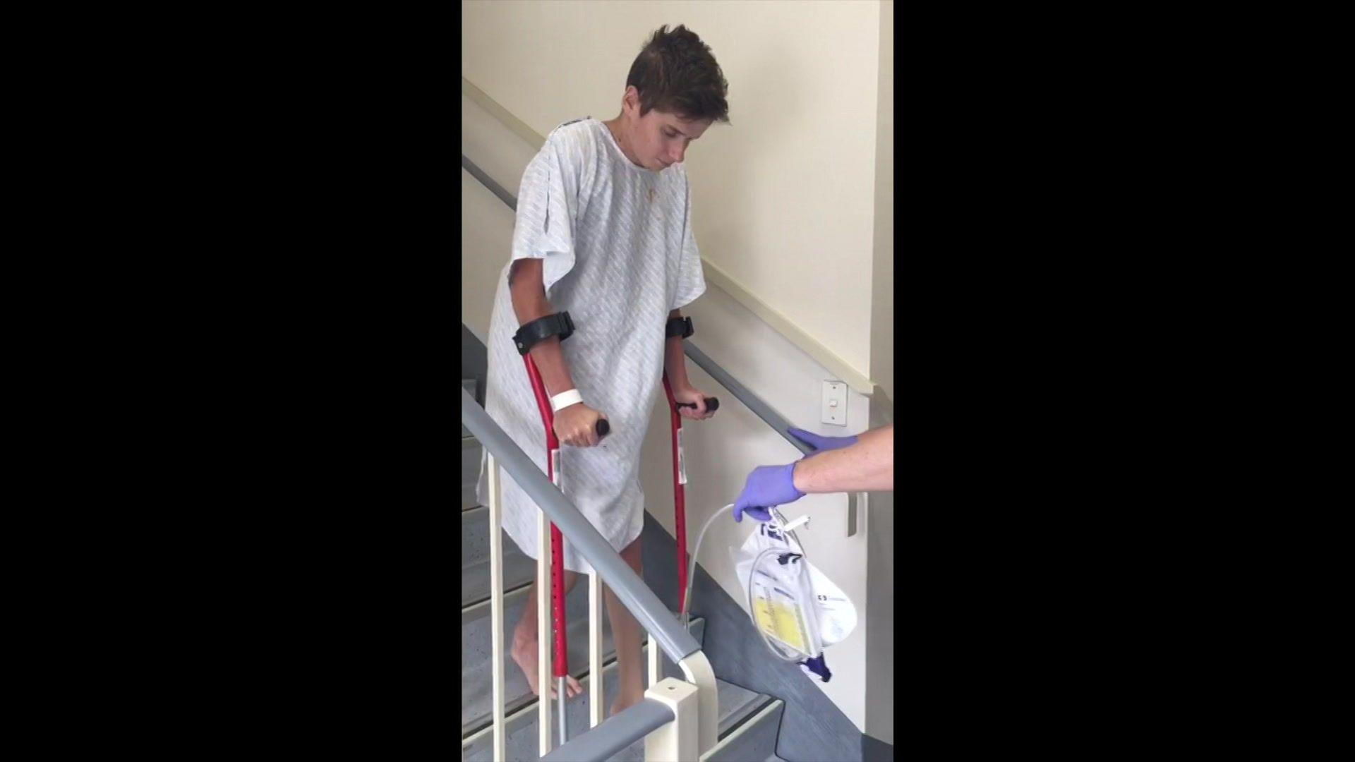 Ed Caudwell coming down the stairs at the hospital after his accident. He is being assisted by staff and he is on crutches.