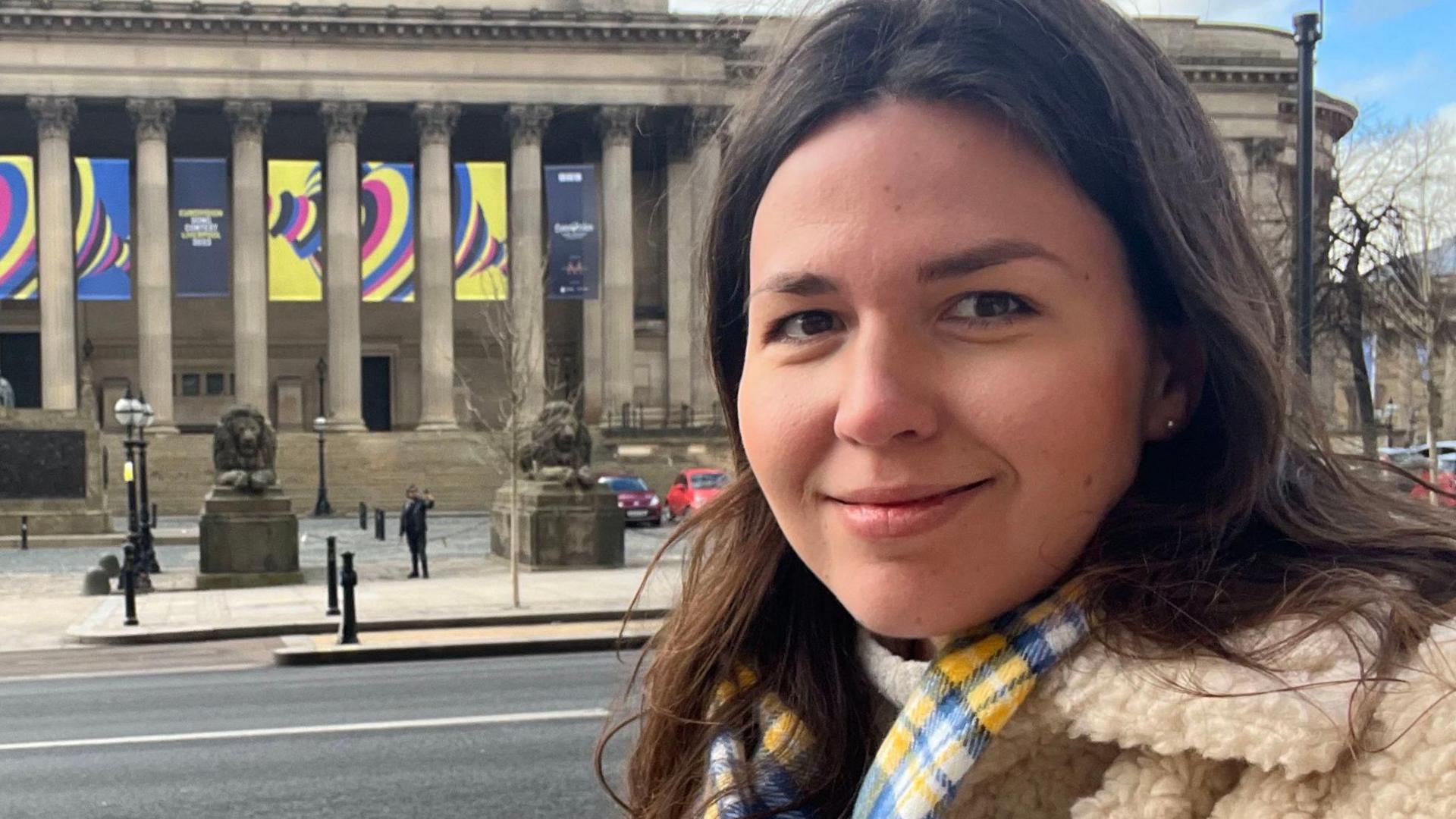 Maria Romanenko smiles outside St George's Hall in Liverpool which is decorated with yellow Eurovision displays.