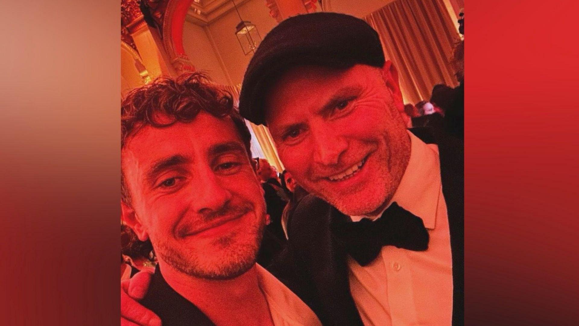 Actor Paul Mescal with Aidan, the official photographer of Gladiator 2 on the red carpet. Aidan wears a tux, with dickey bow and also has a flat cap. 