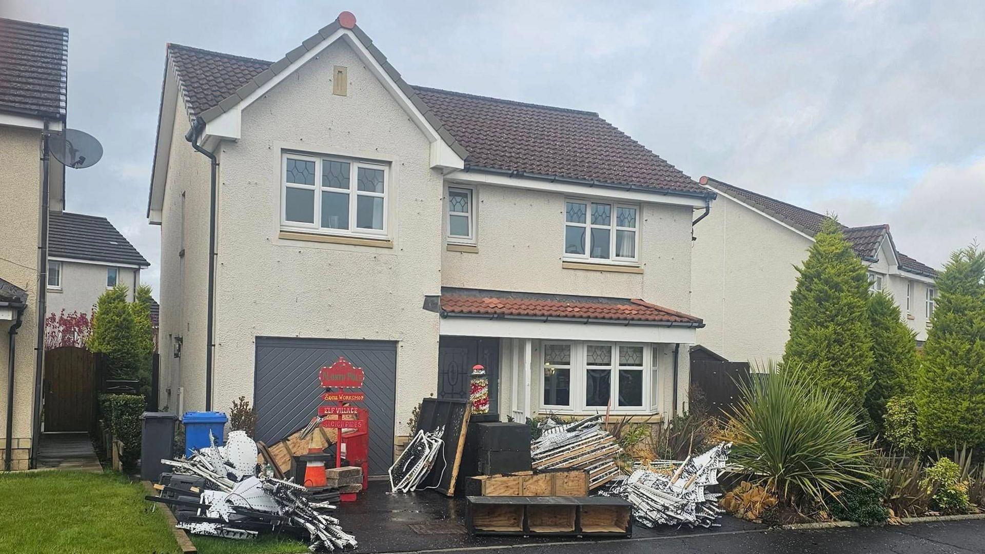 A house with piles of Christmas decorations across the front garden. 