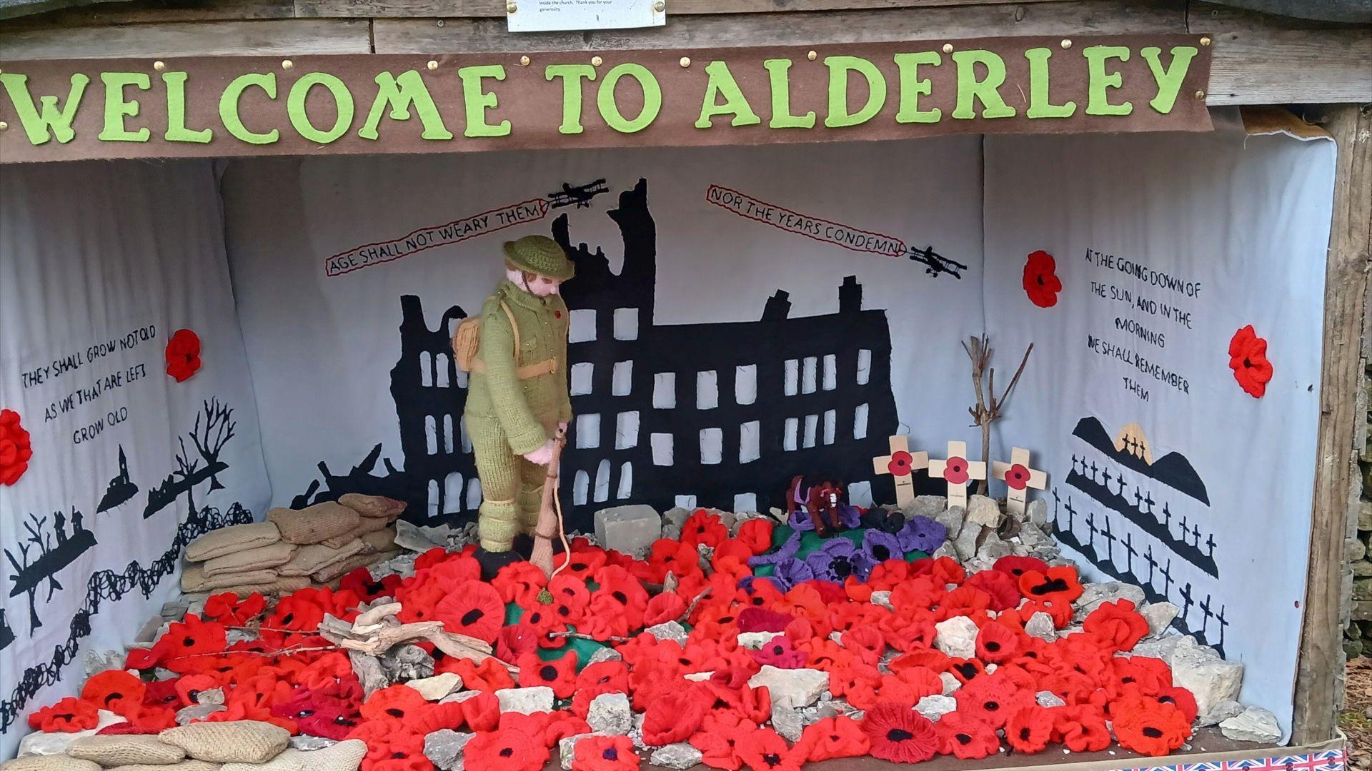 Knitted display in Alderley of a remembrance scene with lots of knitted poppies surrounding a soldier.