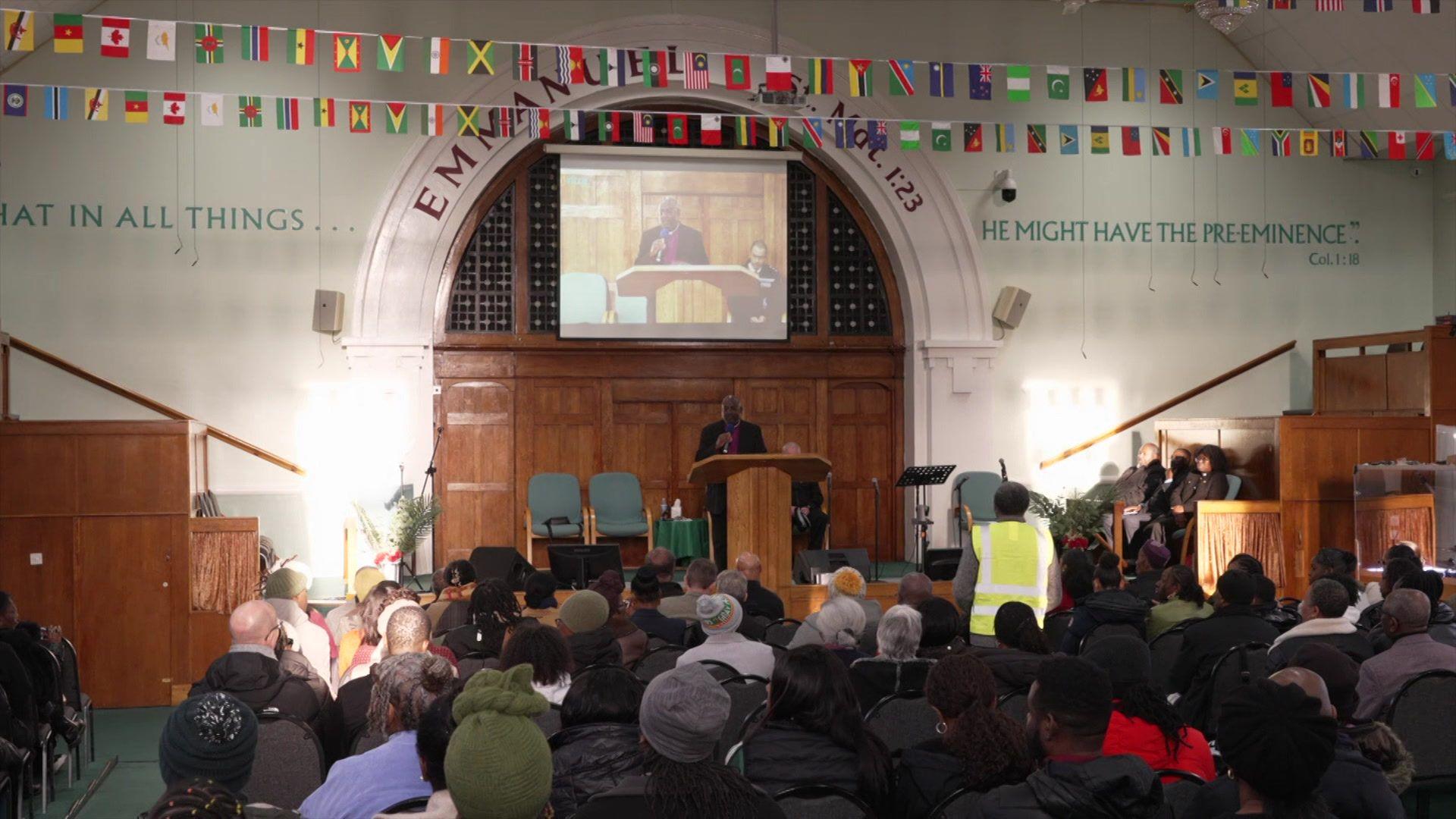 Congregation at The New Testament Church of God in the Harehills area of Leeds. Lots of flags are decorating the stage area.