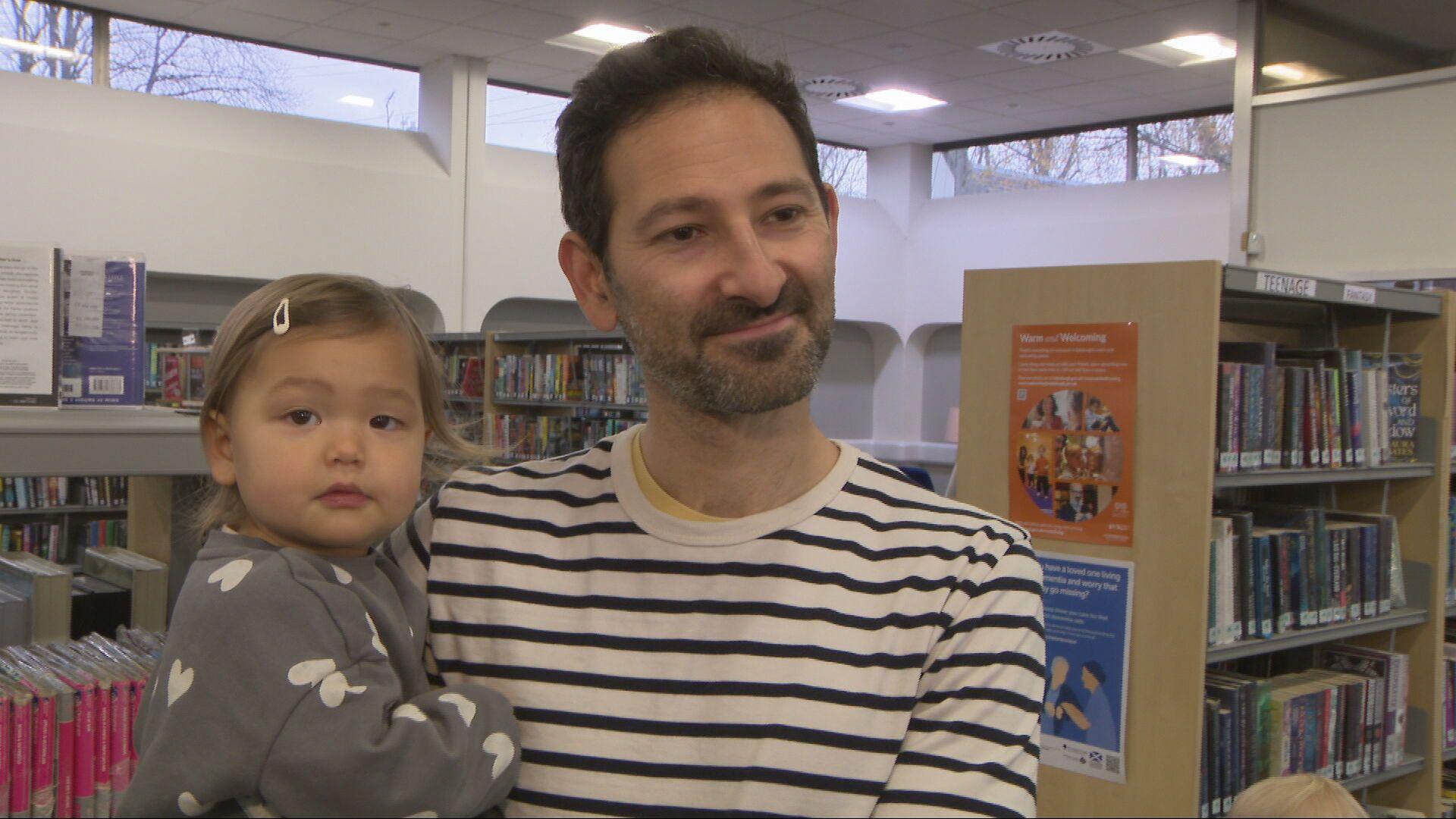 A father holding his toddler daughter in a library