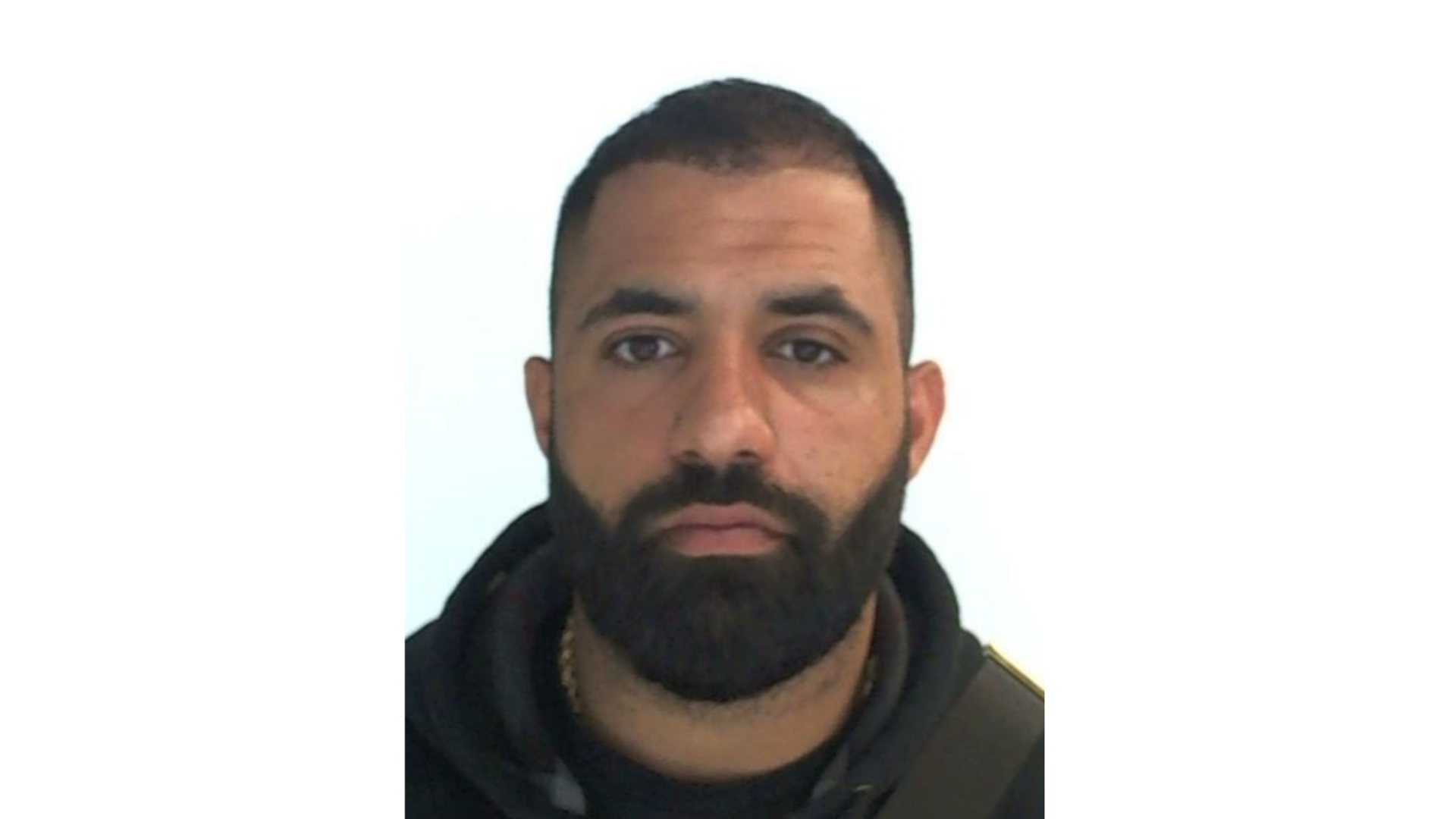 Interpol mugshot of Ismail Abdo. He has very short dark hair and a thick but short dark beard.