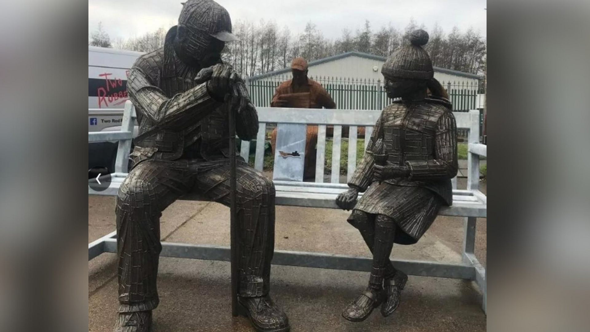 A metal sculpture of a man and a young girl on a bench