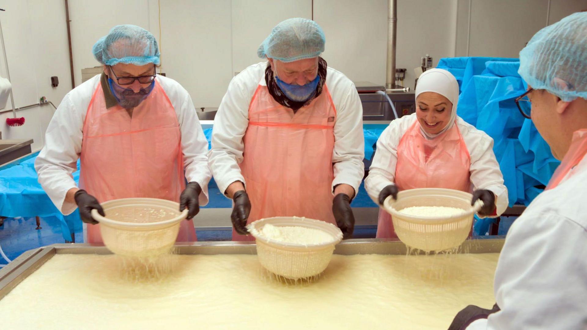 Pictured in 2021, TV chefs The Hairy Bikers are making cheese with the owners of the Yorkshire Dama Cheese company. All are wearing hair coverings and gloves and are using sieves. 