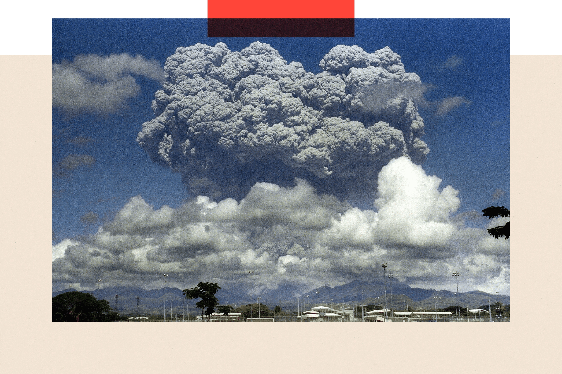 Mount Pinatubo with enormous grey clouds above it against a blue sky following its eruption in 1991