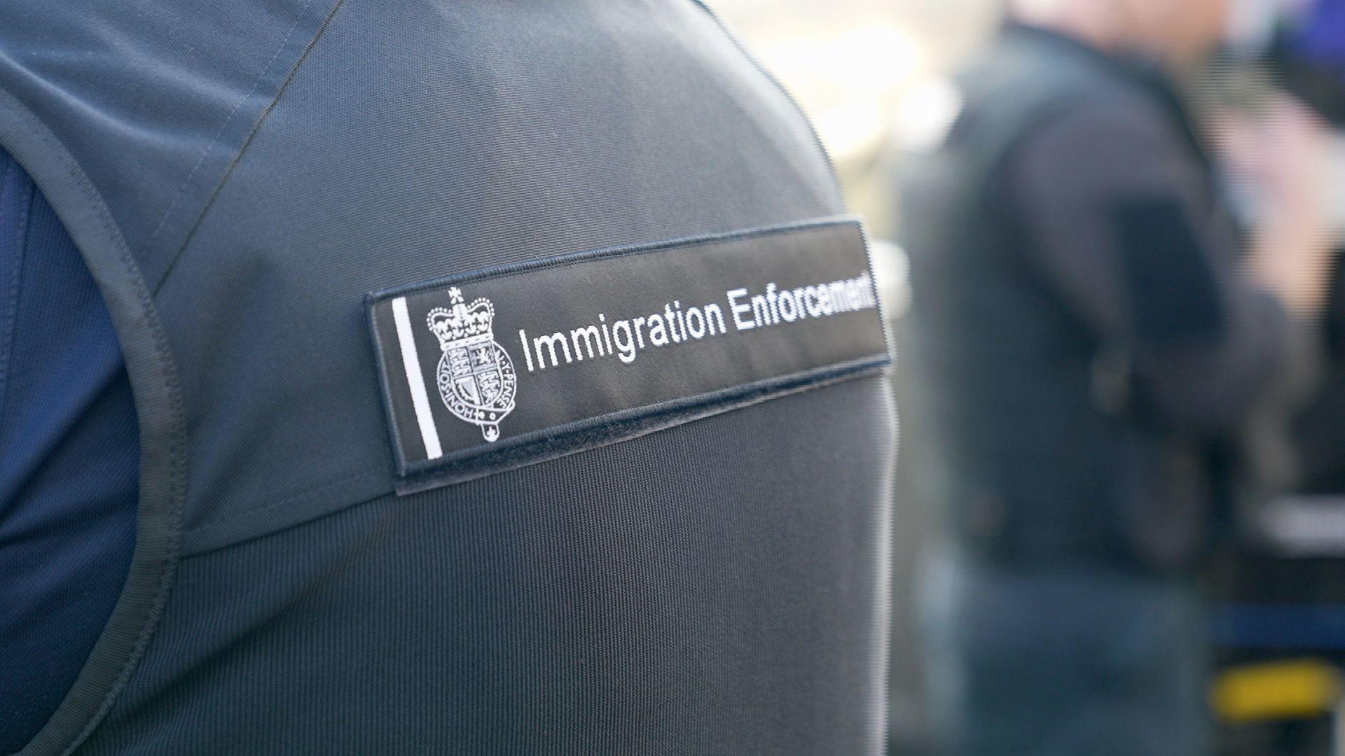 A zoomed in photo a person wearing an Immigration Enforcement uniform which is navy blue in colour. 