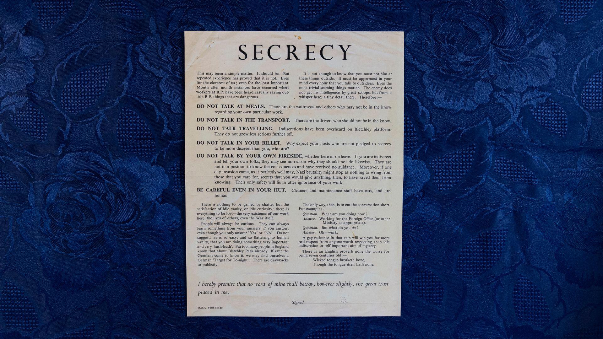 A document listing what workers at Bletchley Park can and cannot do during their term of employment. It has been placed on a blue, floral background. It includes phrases such as do not talk at meals, do not talk in the transport, and do not talk in your billet.