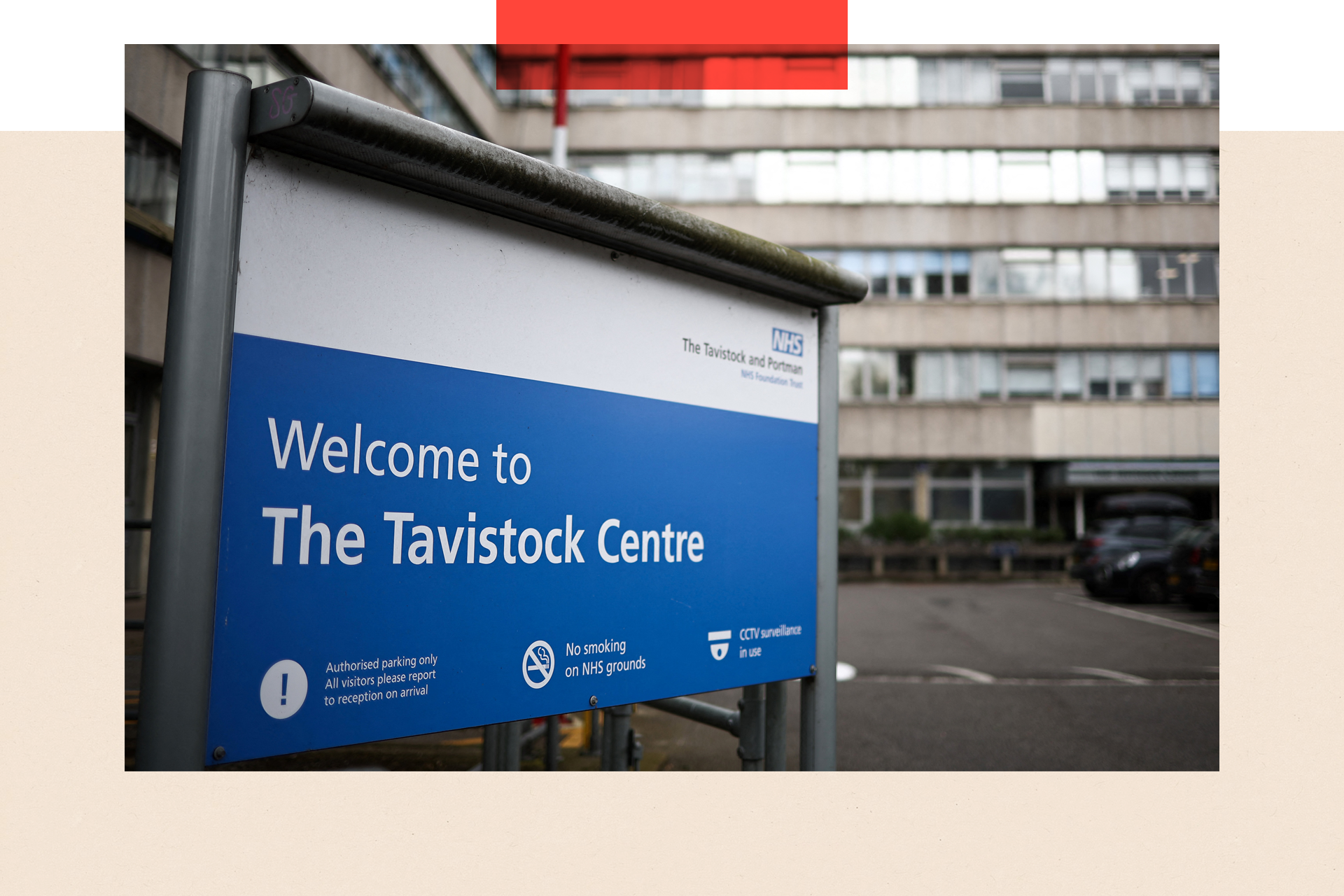 An NHS sign that reads "Welcome to the Tavistock Centre". It is on a blue background and mounted on posts. Behind it is a grey building and the edge of a car park.