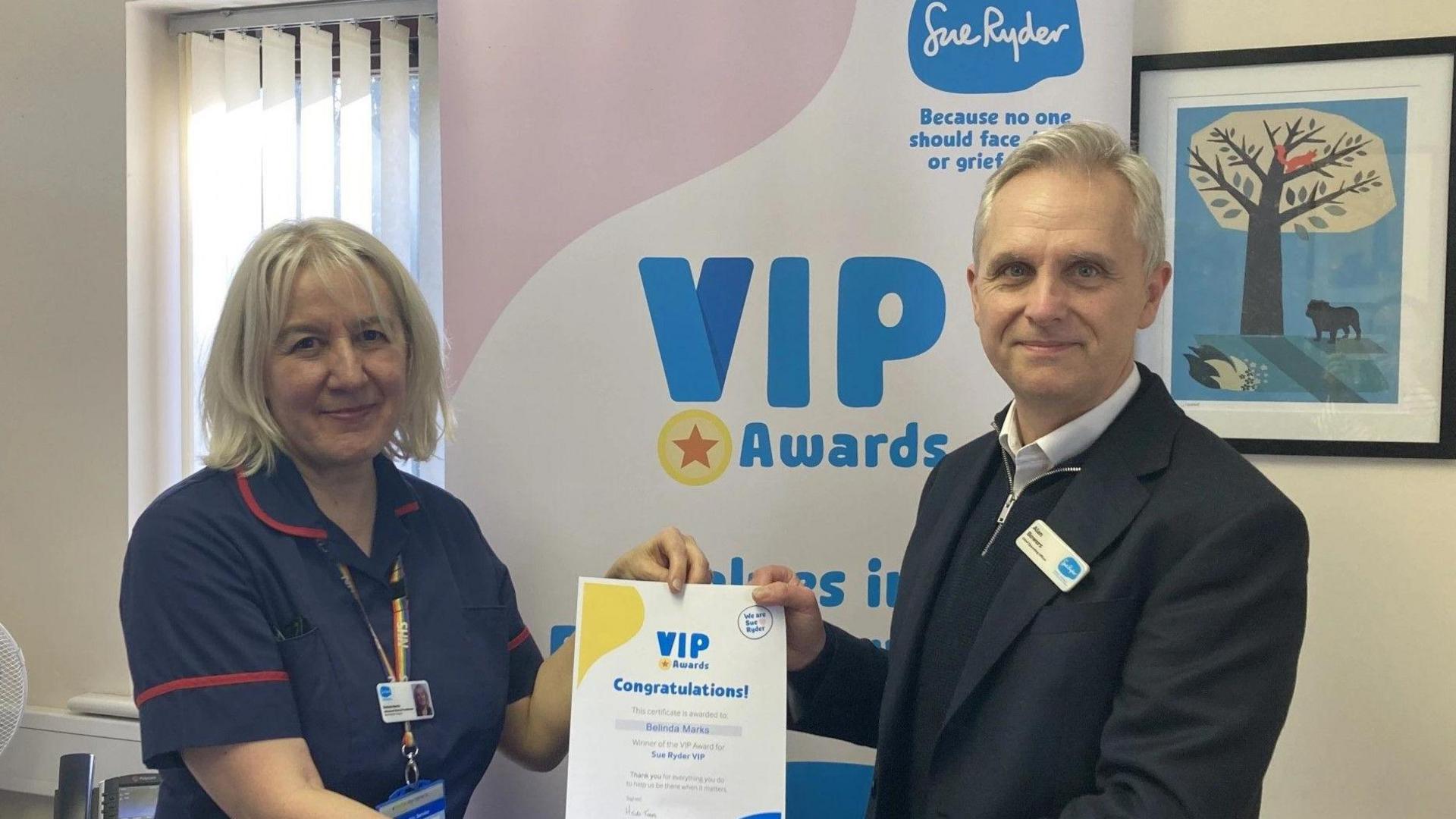 Belinda Marks receiving a certificate from Sue Ryder chief operating officer Alan Bowers