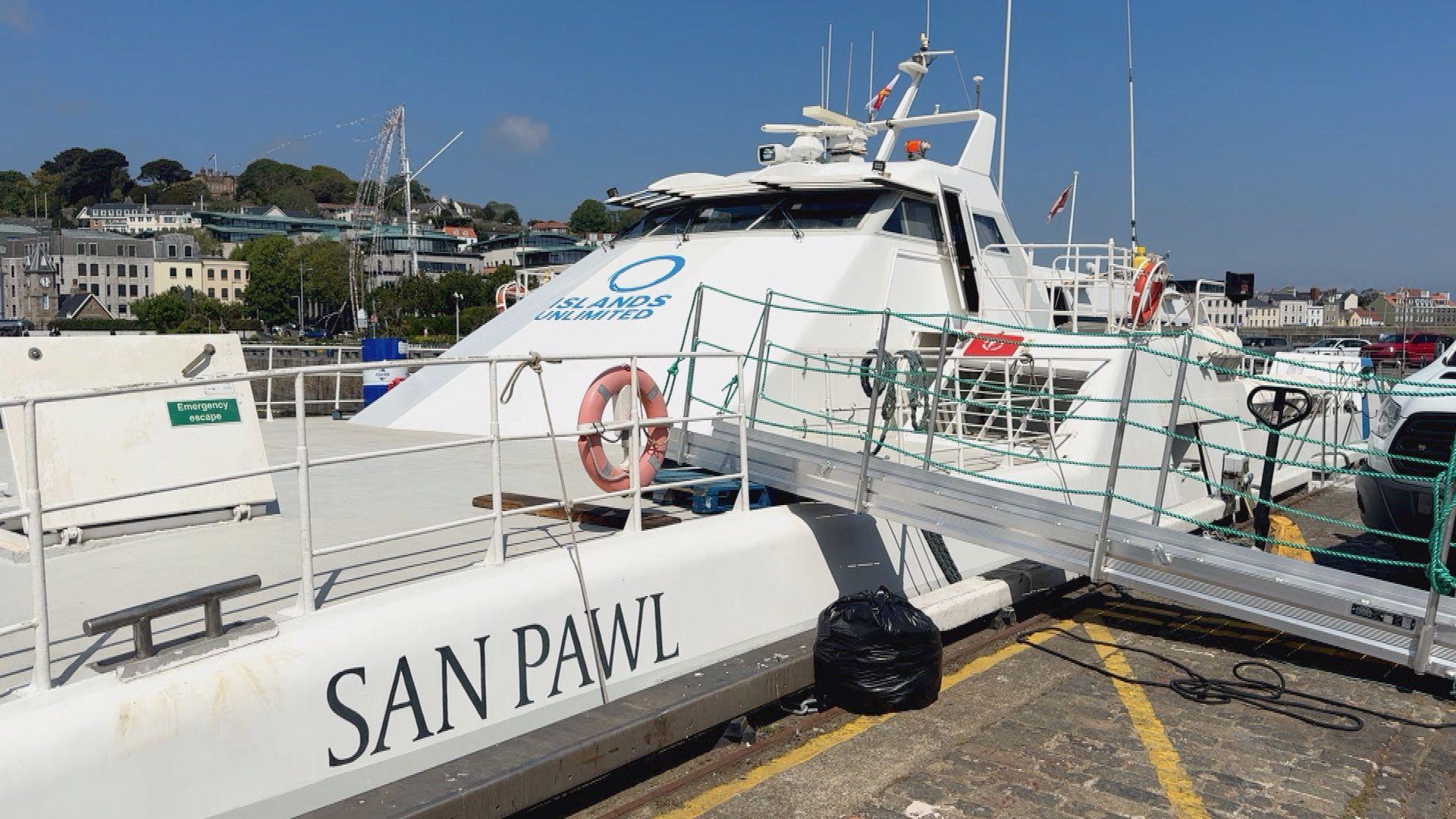 Islands Unlimited boat, San Pawl, a catamaran style vessel. There is a ramp leading on to the boat. In the background is housing.