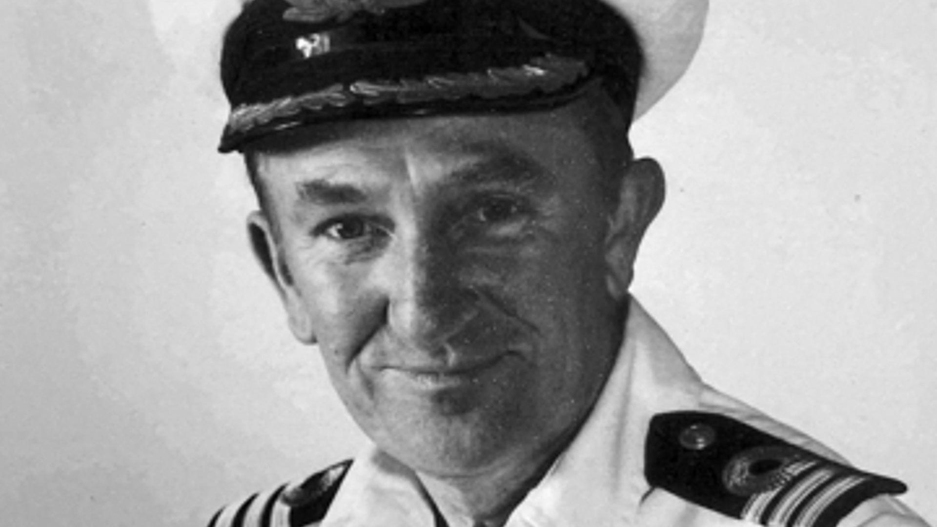 An old black and white photo of a man wearing a naval uniform, including a hat. He is smiling at the camera.