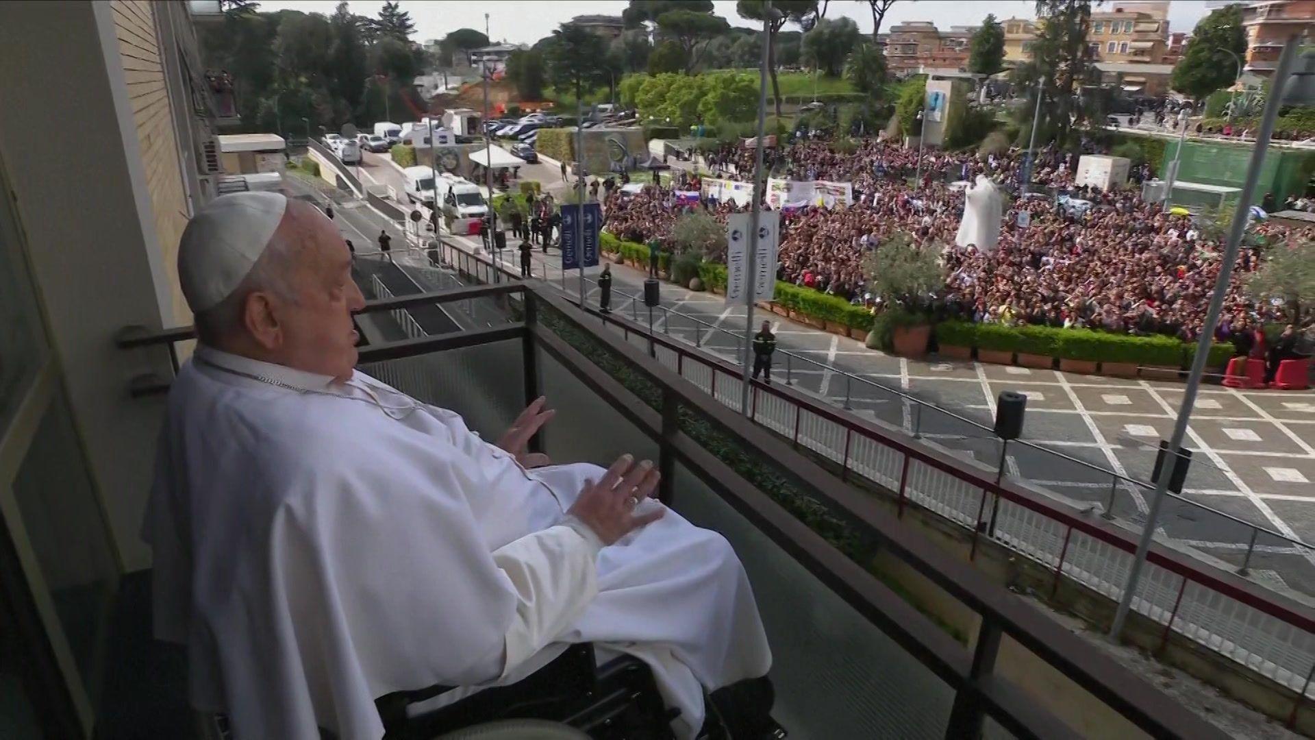 Pope Francis waves at crowds from the balcony of his suite at Gemelli hospital in Rome. 