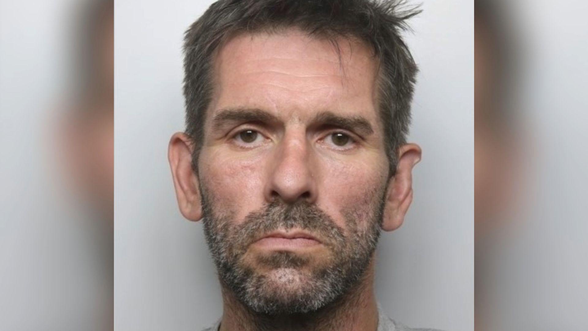 A police mugshot of Wayne Bond, a man with a stubbly beard and short brown hair. He is stood against a pale backdrop.