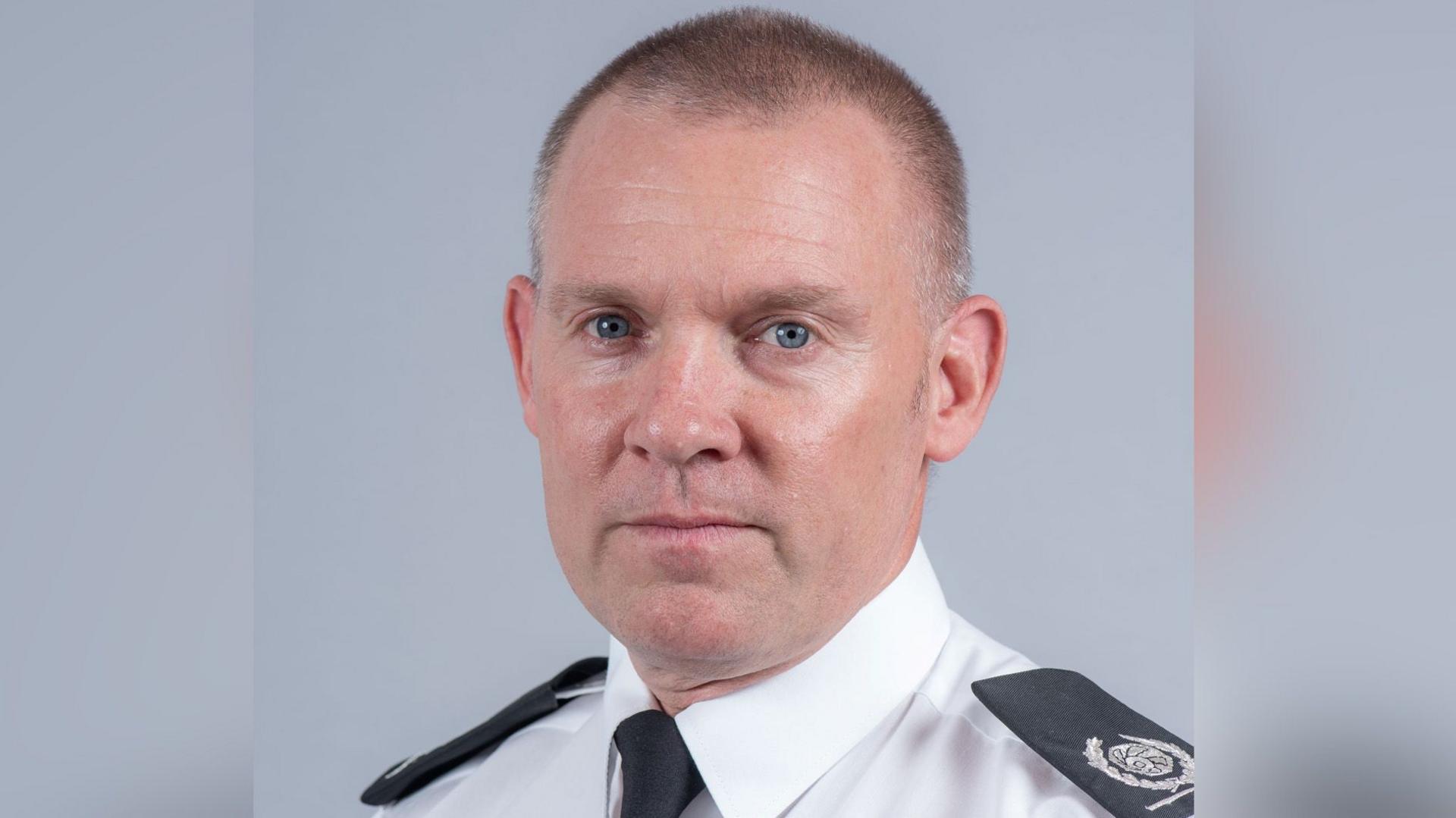 Emyr Gough, from Norfolk Fire and Rescue Service, in a white shirt and black tie with epaulettes on his shoulders.