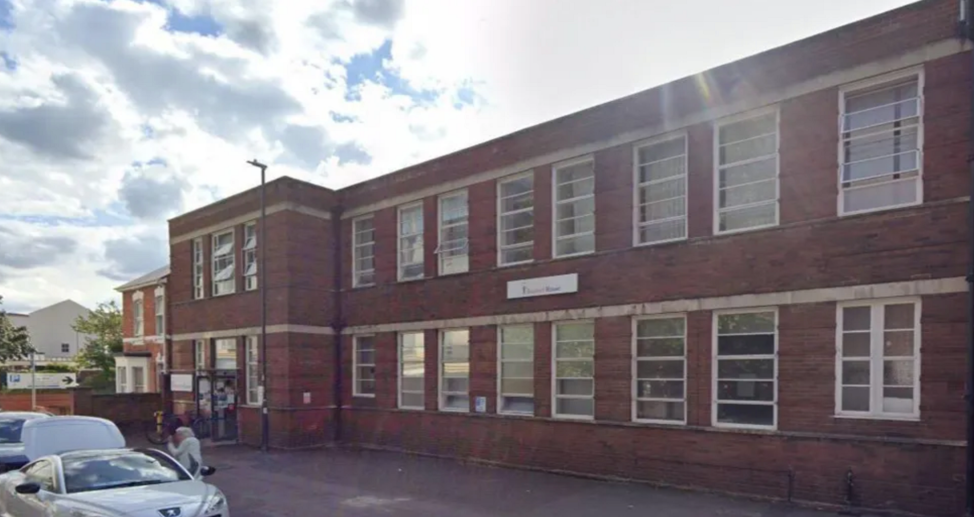 The Swindon Carers Centre. It is a two-storey red brick building with several windows with white wooden panels all across it