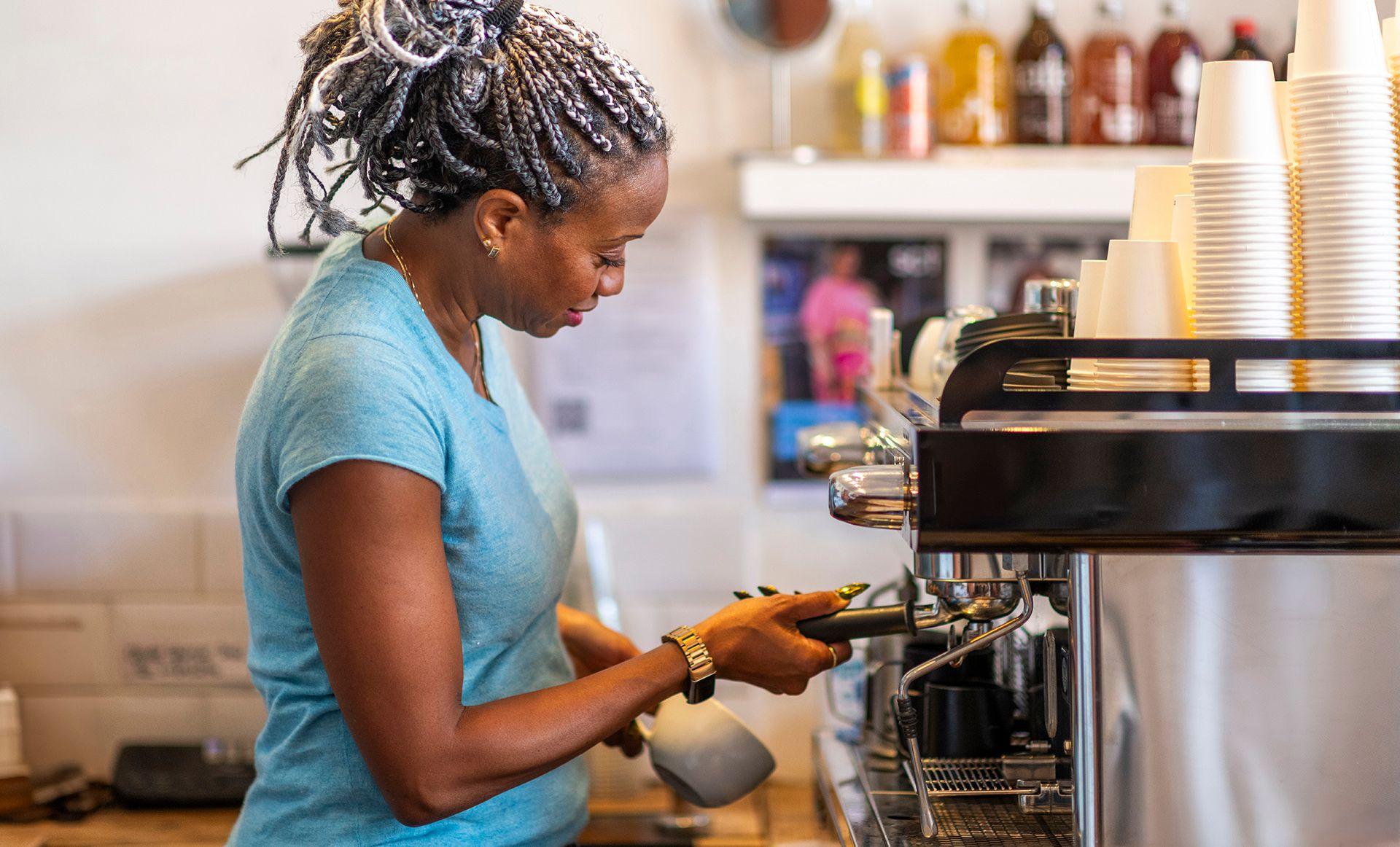 Stock photo shows a barista making coffee at an espresso machine in a coffee shop in the UK