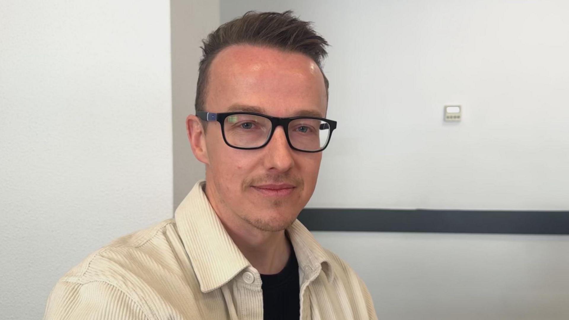 Man in glasses with brown hair looking at camera