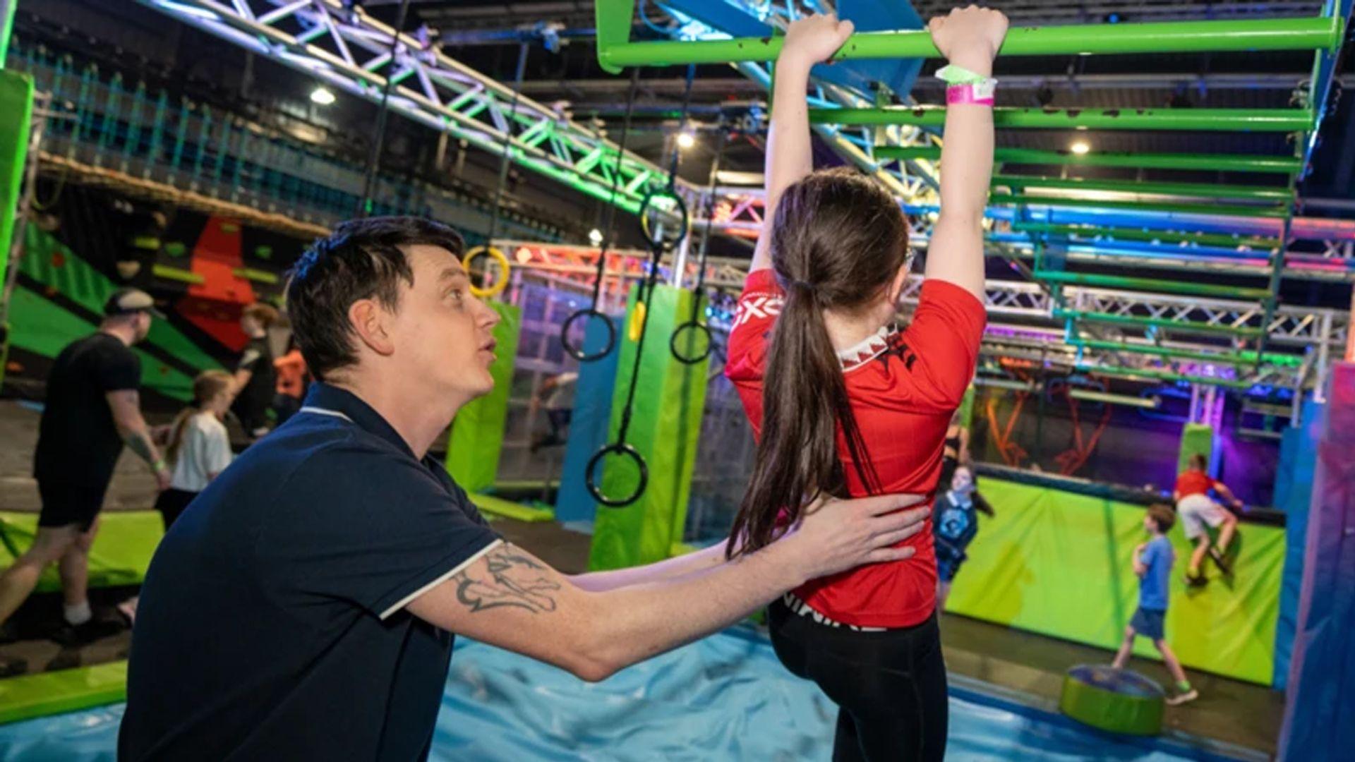 a parent playing with their child and an inflatable adventure park.