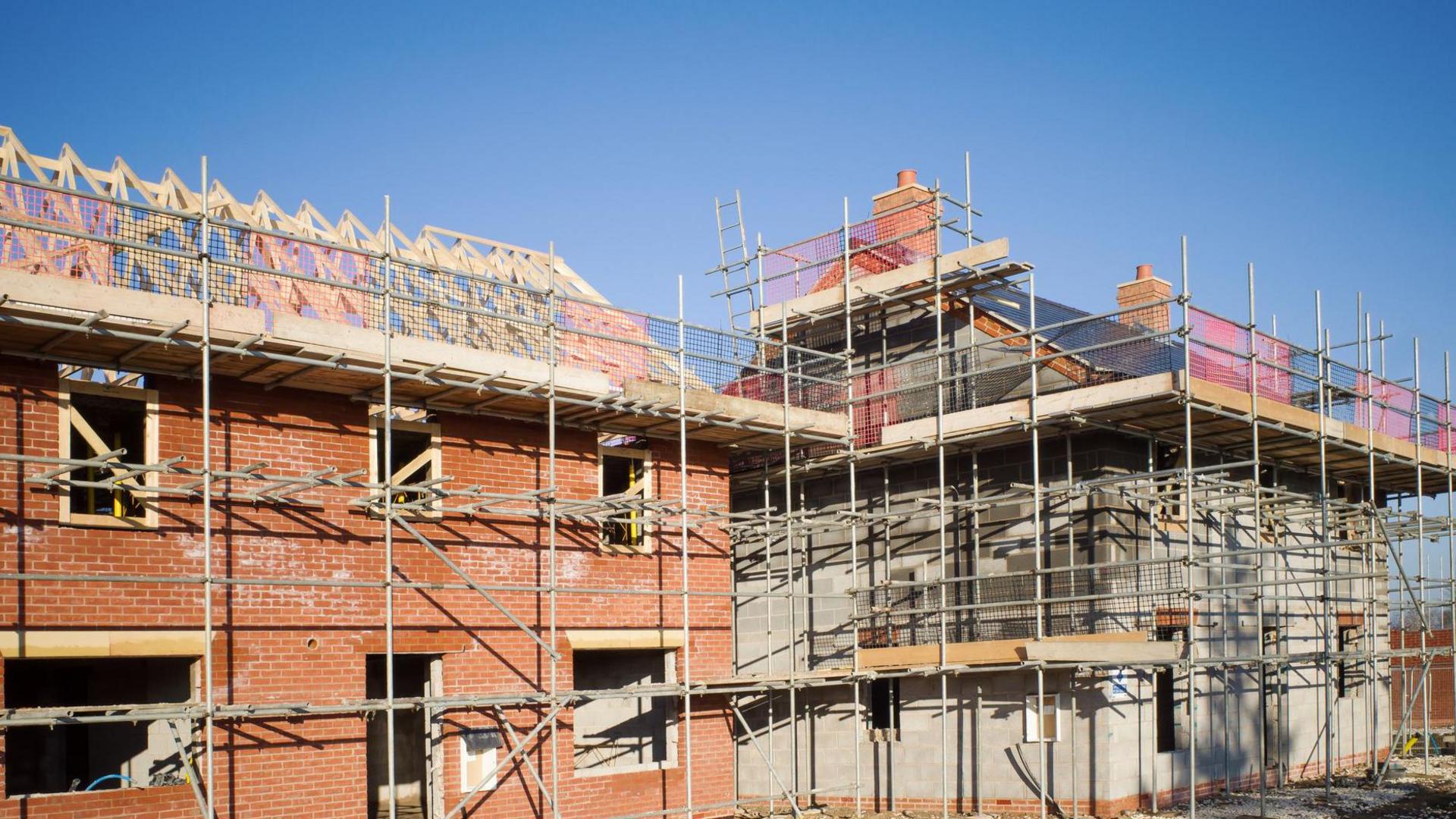 A building site with a number of brick built homes, with timber frames and scaffolding