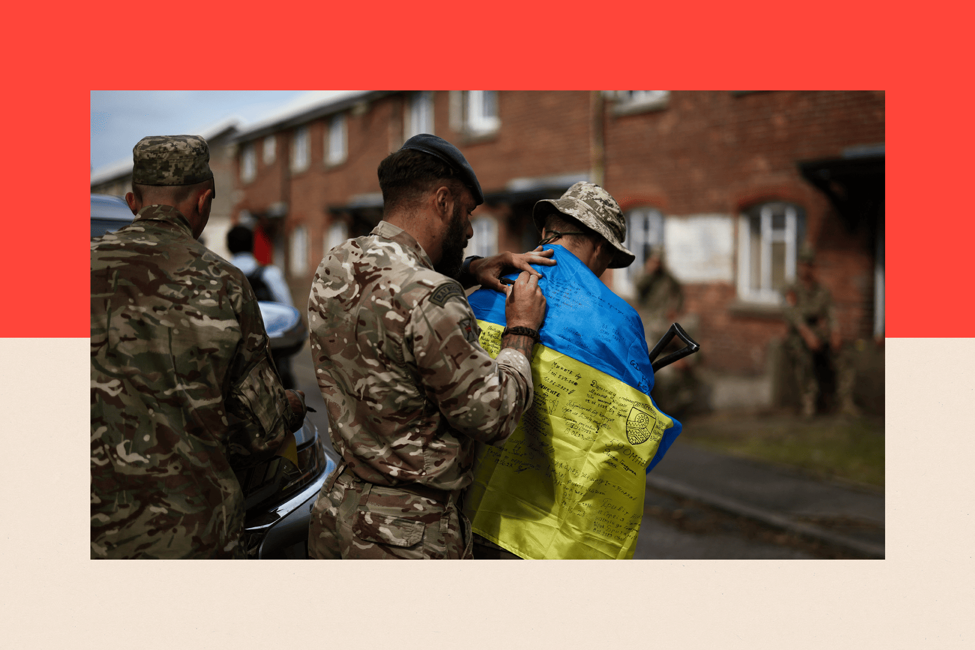 A member of Britain's RAF Regiment signs the Ukraine's flag of a Ukraine Army