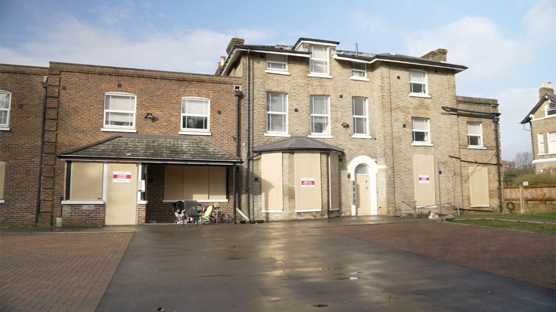 A building with locked doors and boarded windows with children's toys and bicycles left outside