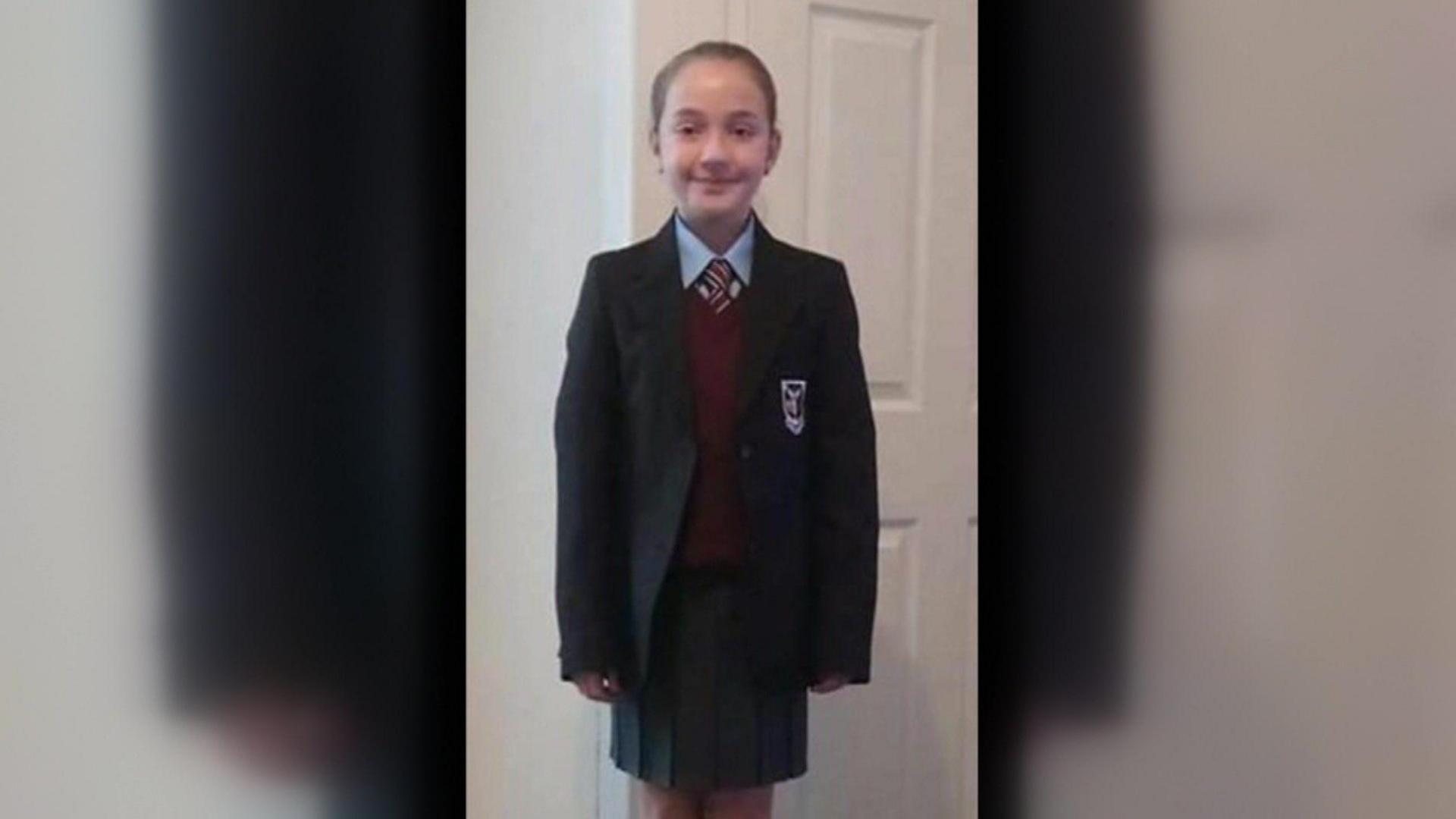 A younger Miah in her school uniform smiles at the camera