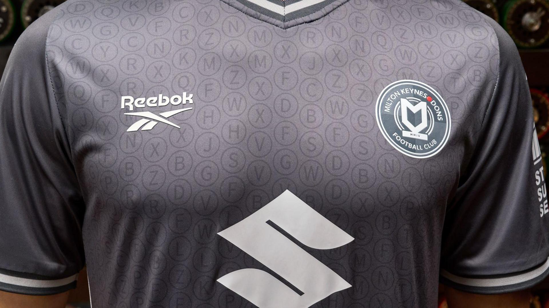 A close up of the new MK Dons kit shows the Reebok logo, the MK Dons logo and enigma machine keys subtly imprinted into the fabric in a recurring pattern.