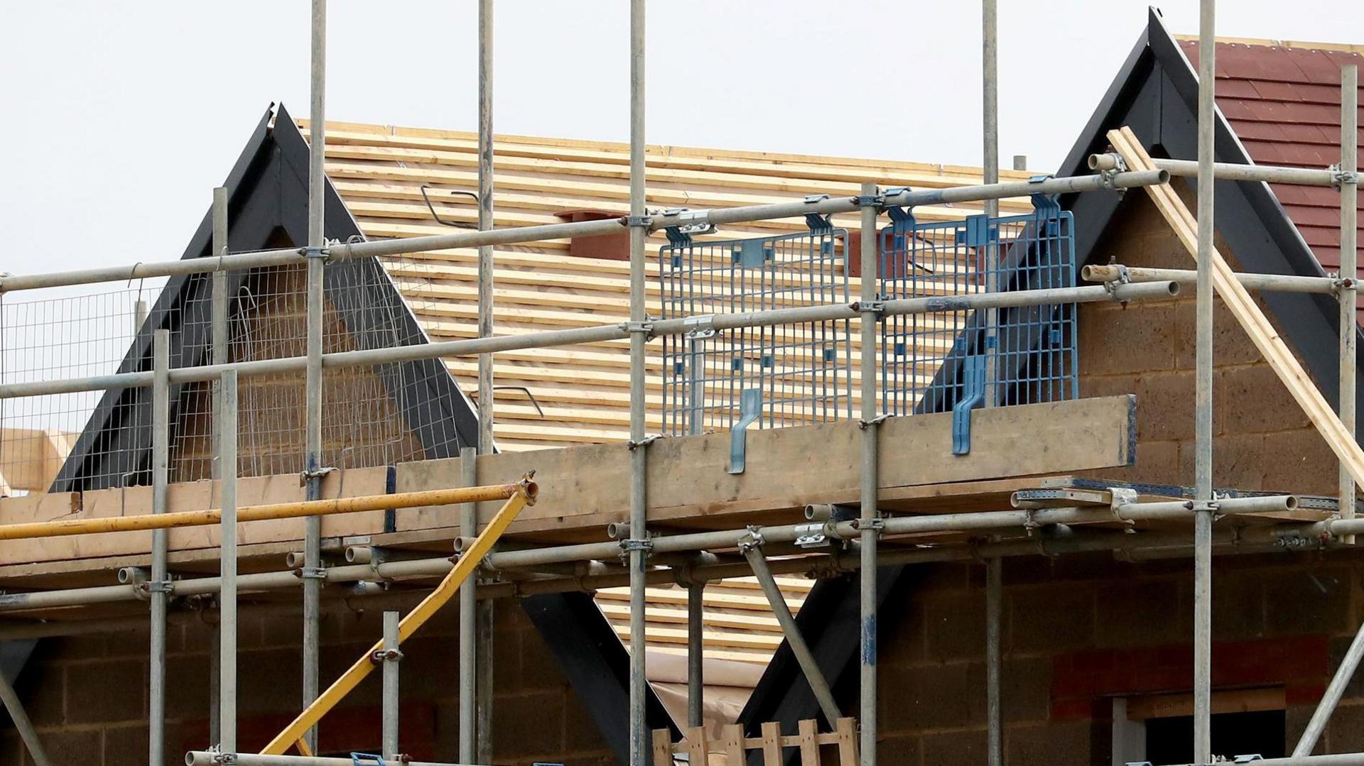 Scaffolding surrounding the roofs of new houses being constructed.