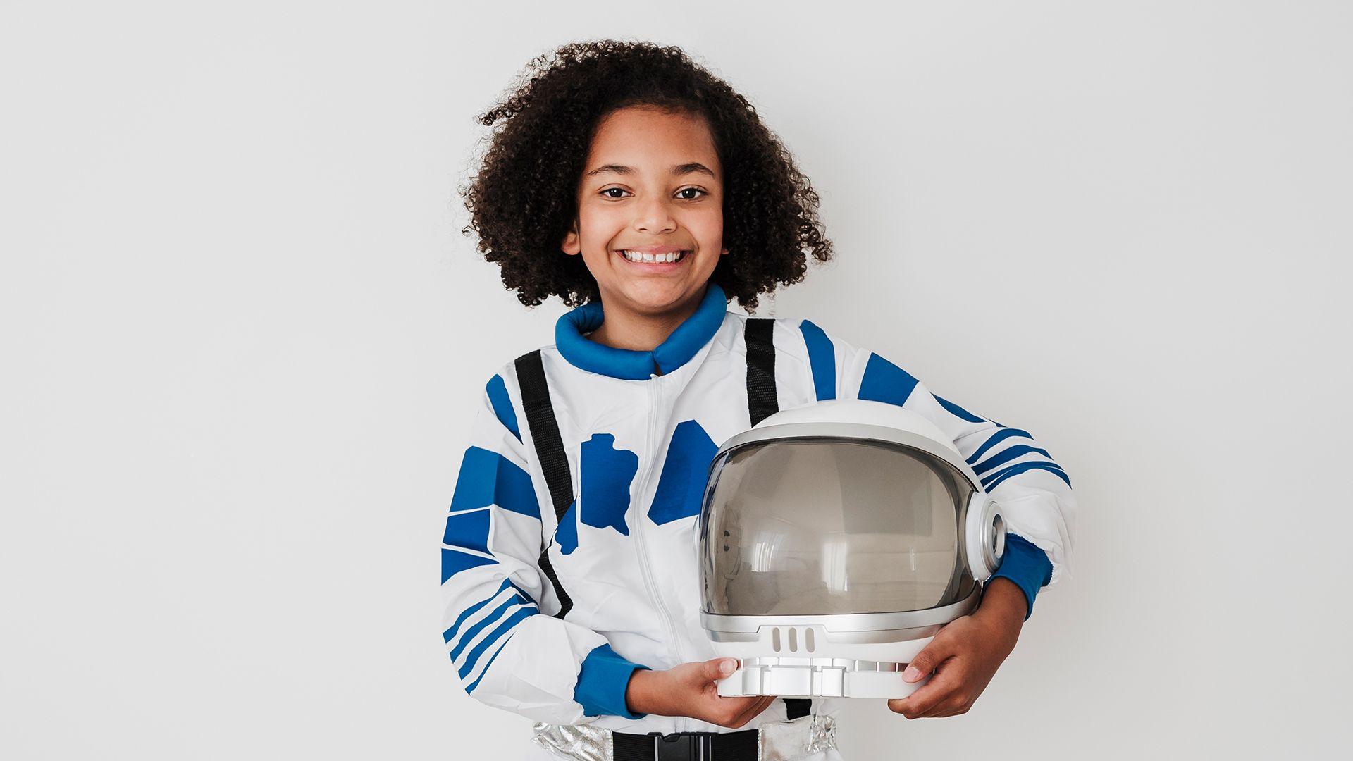 A child in an astronaut costume, holding a space helmet