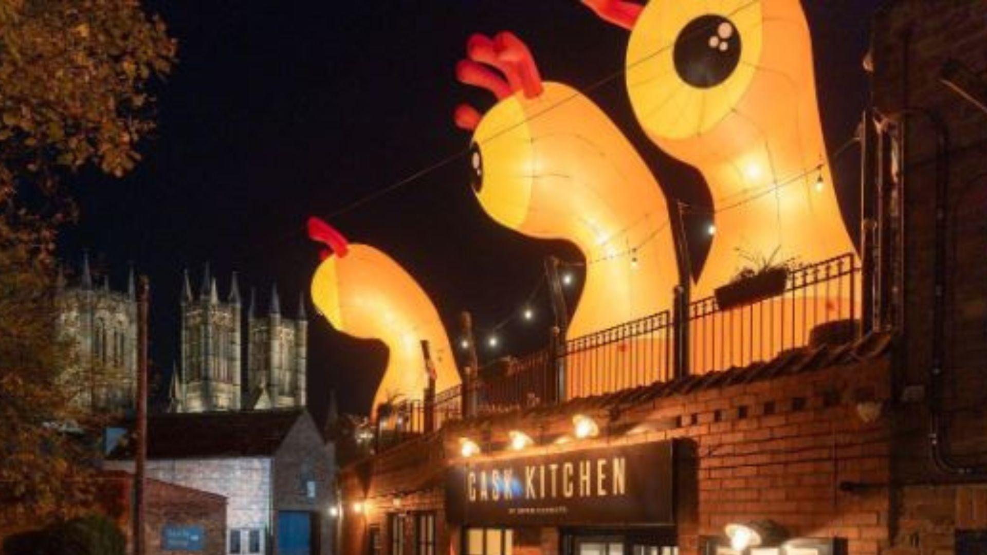 Three orange single-eyed with red antennas above a restaurant labelled Cask Kitchen.