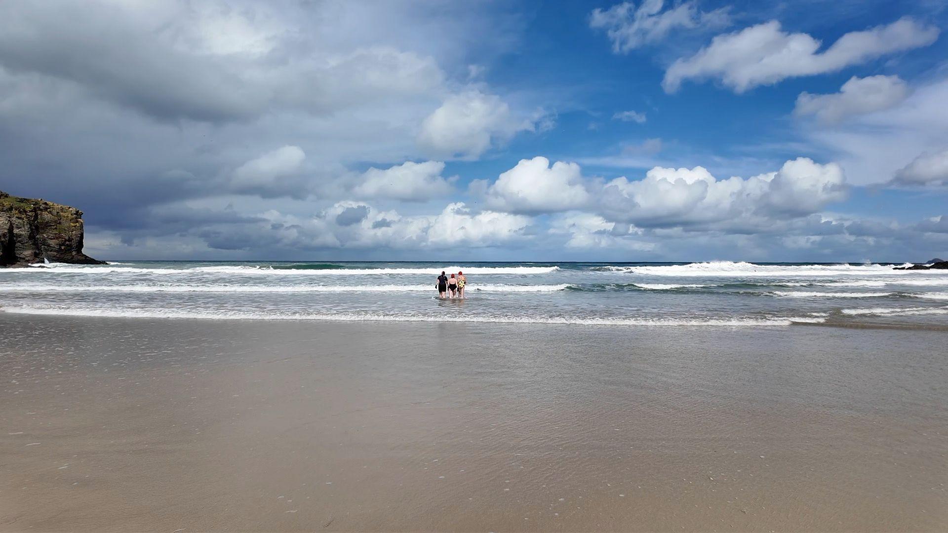 Swimmers entering the water at a beach in Cornwall. 