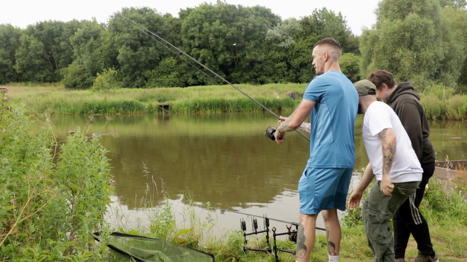 A group of three men fishing at a water's edge