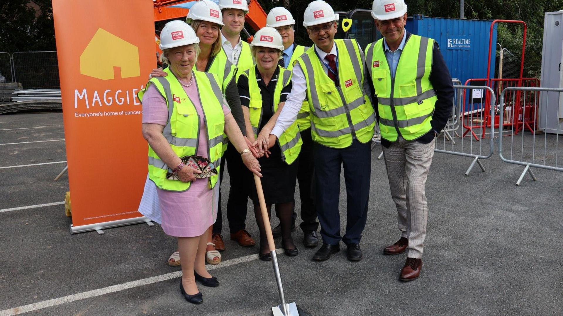 Several people standing around a spade with Maggie's sign behind 