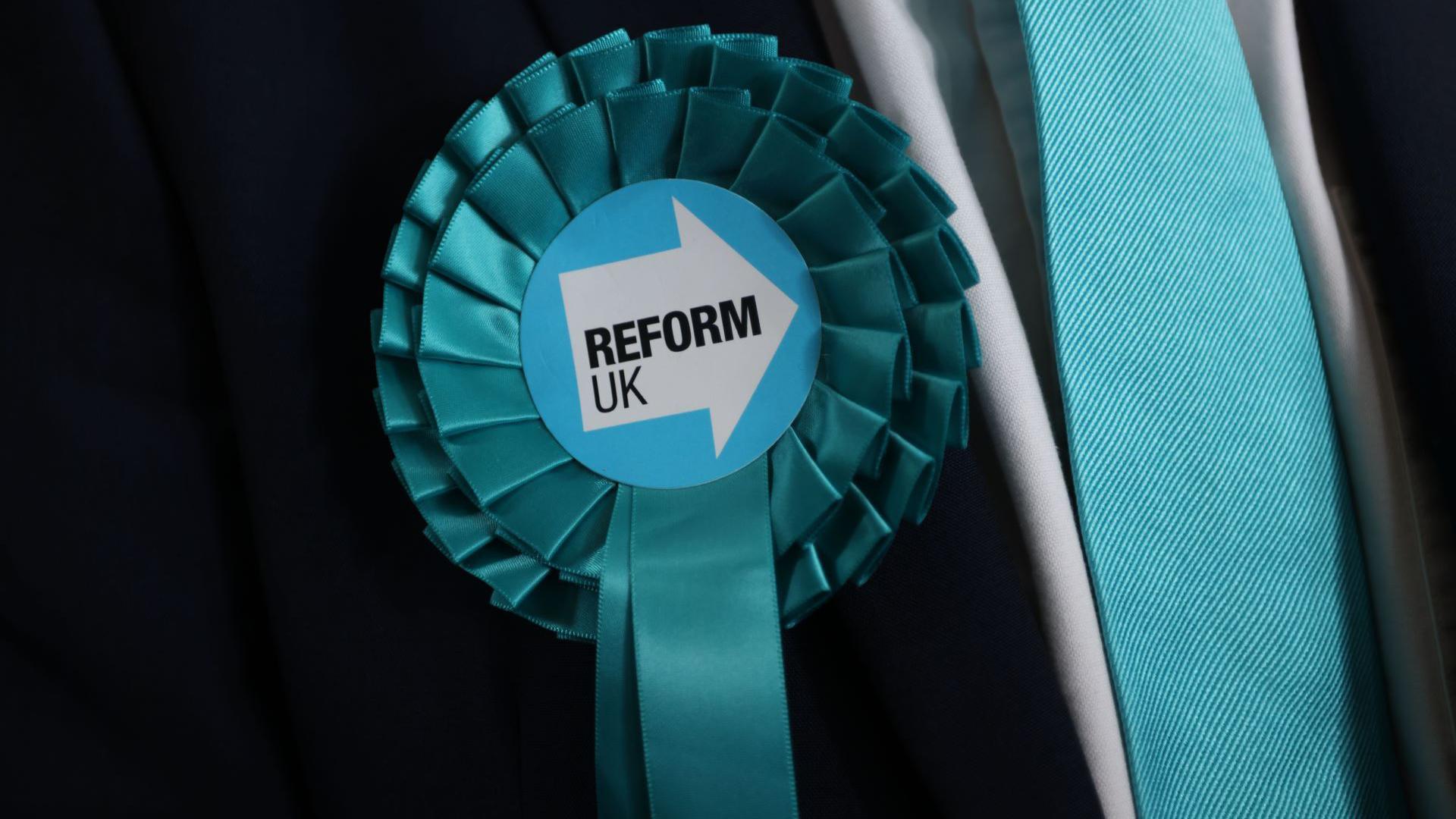 A turquoise rosette for the Reform Party pinned to a suit.