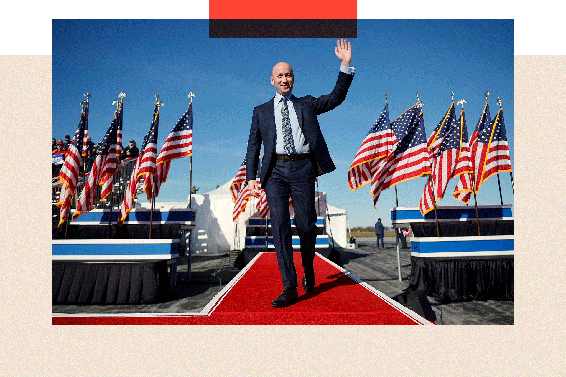 Stephen Miller arrives for a campaign rally for Republican presidential nominee Donald Trump at Lancaster Airport on 3 November 2024 in Lititz, Pennsylvania - pictured walking down a red carpet, wearing a suit and waving, with US flags either side