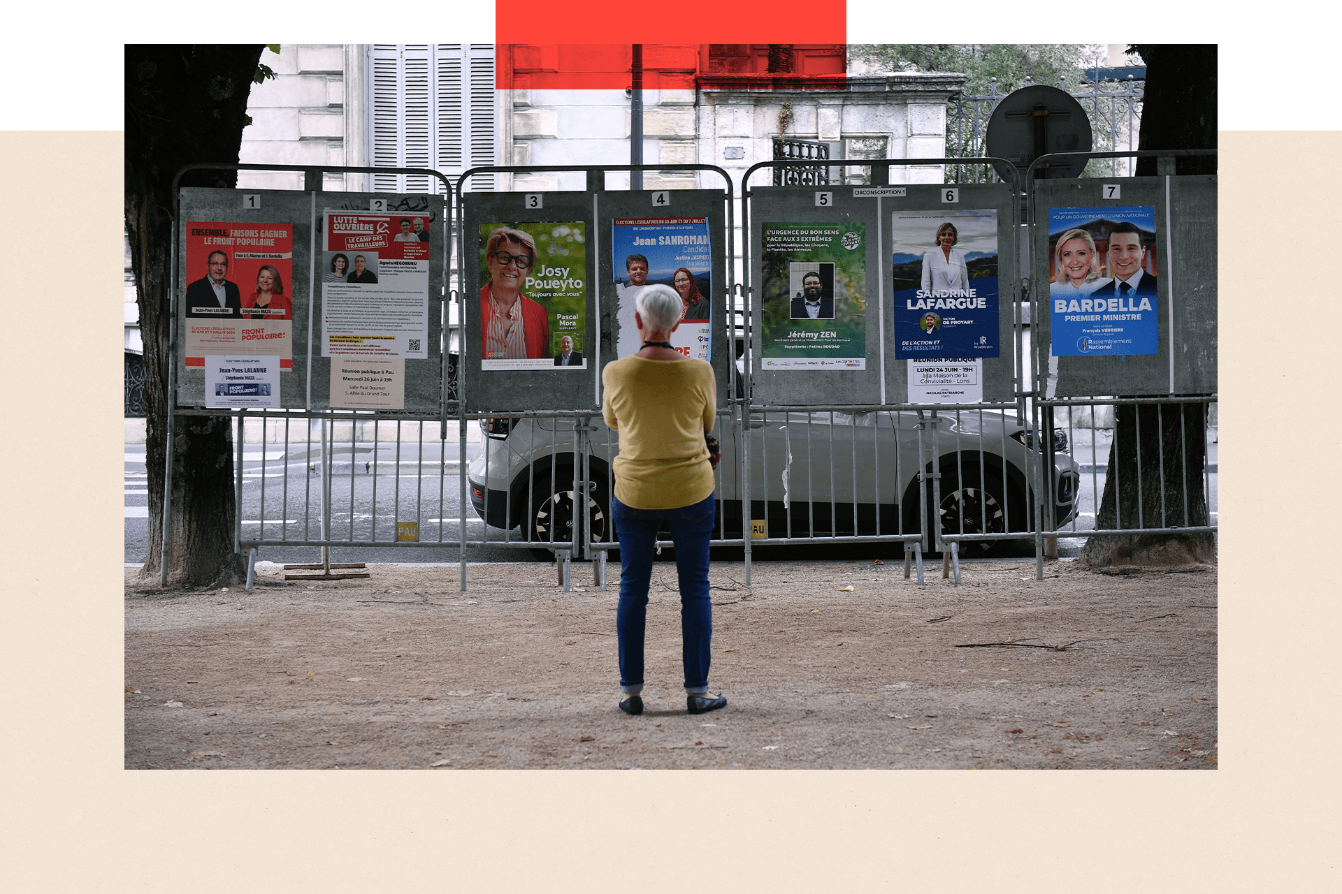 A woman looks at election posters next to a polling station during the first round of parliamentary elections in Pau, south-western France