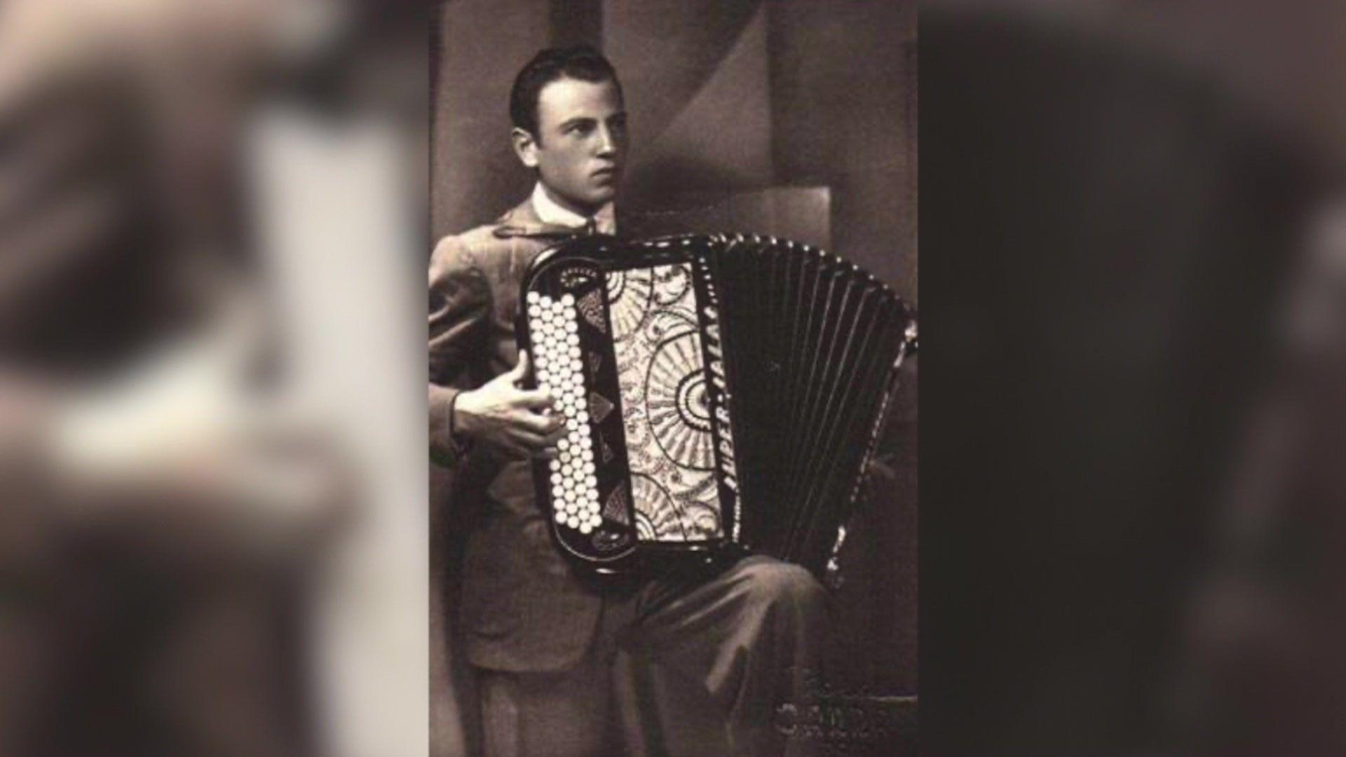 Black and white photo of Bruno Allodi wearing a smart suit, playing his accordion