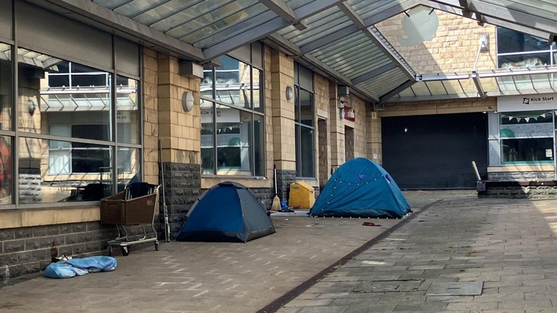 Two blue tents and a trolley on the street in Rawson Place, Bradford.