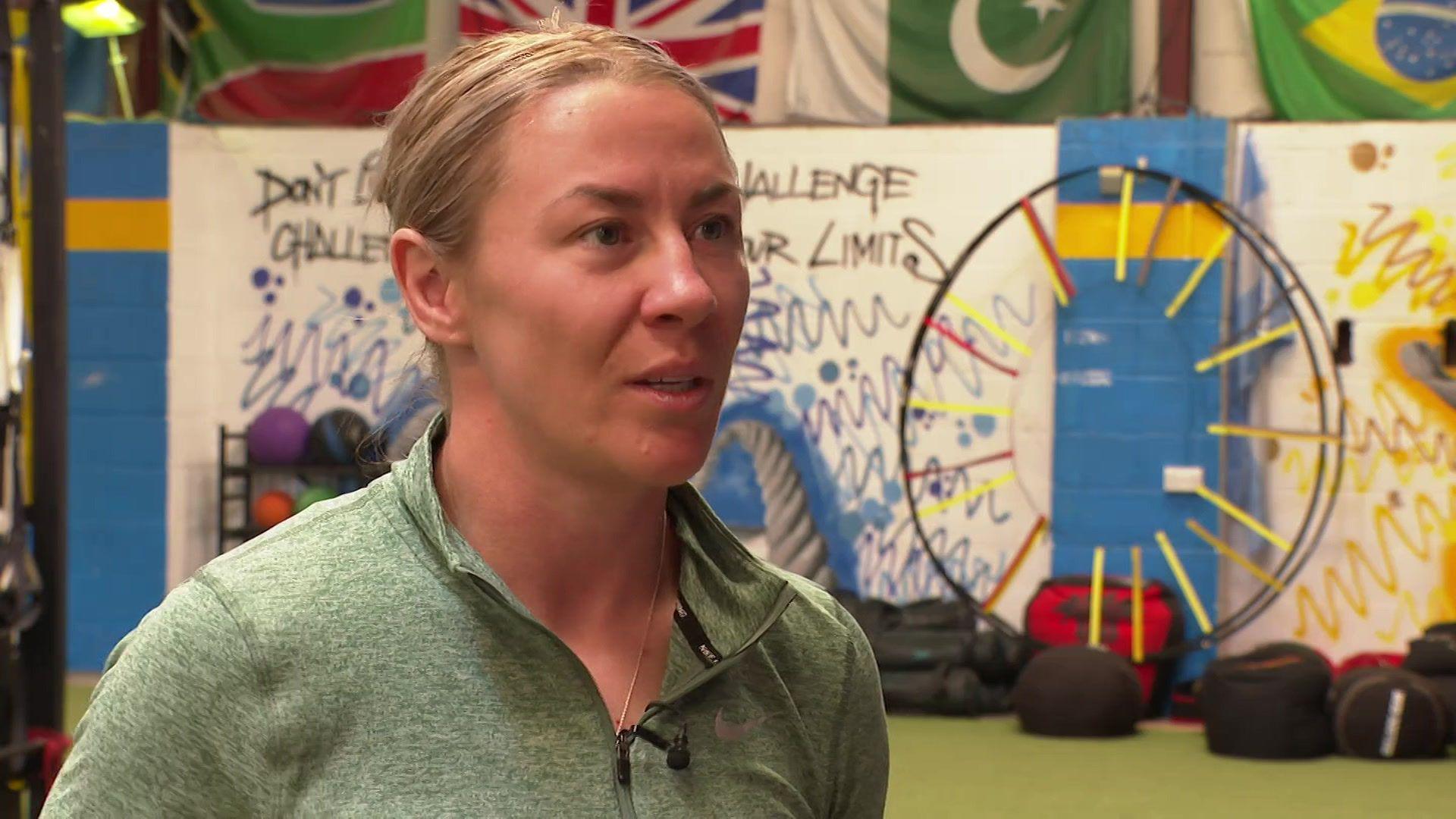 Molly McCann has her blonde hair tied back in a bun and is wearing a green zipped sports top.