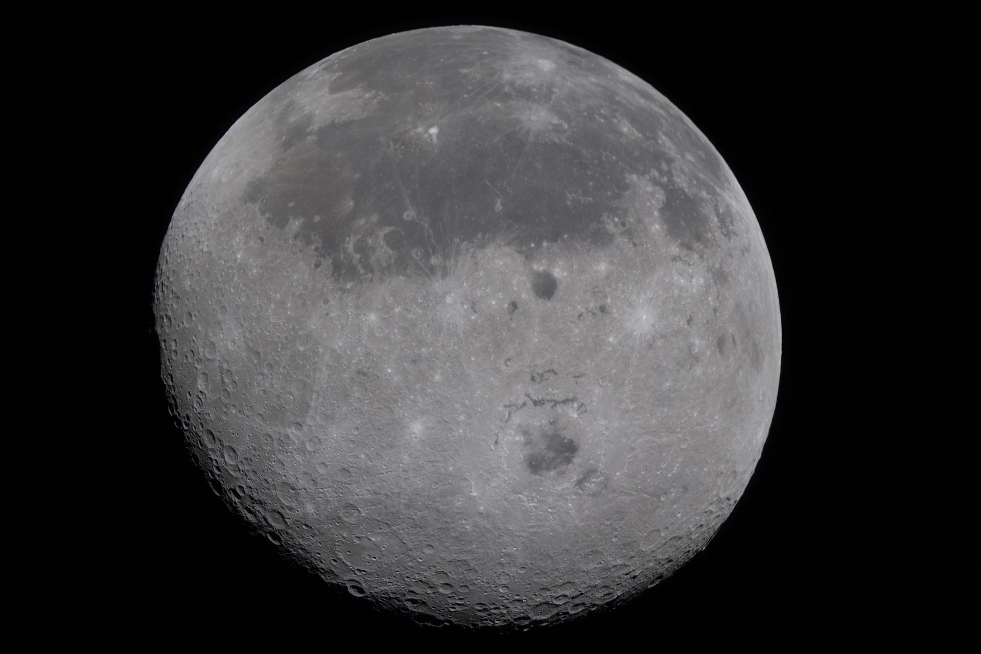 The circle of the grey Moon fill the frame. It is close enough to see the rugged features.
