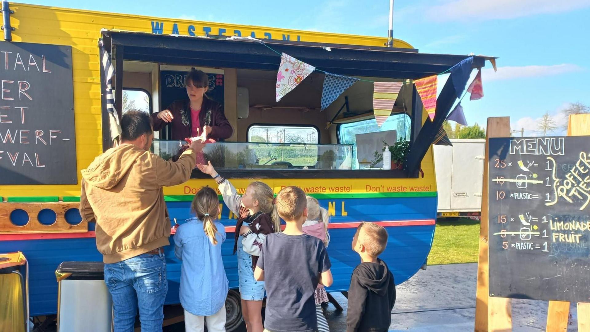 Adult and children are seen queuing outside the food truck