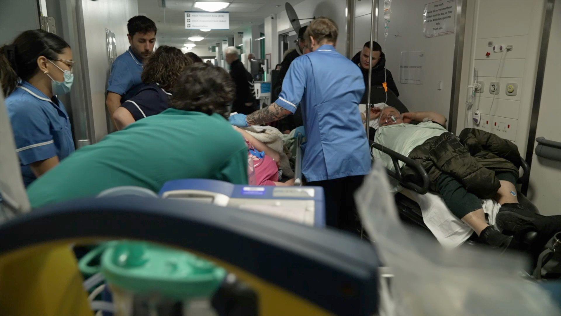 Patient suffering seizure being wheeled through busy corridor