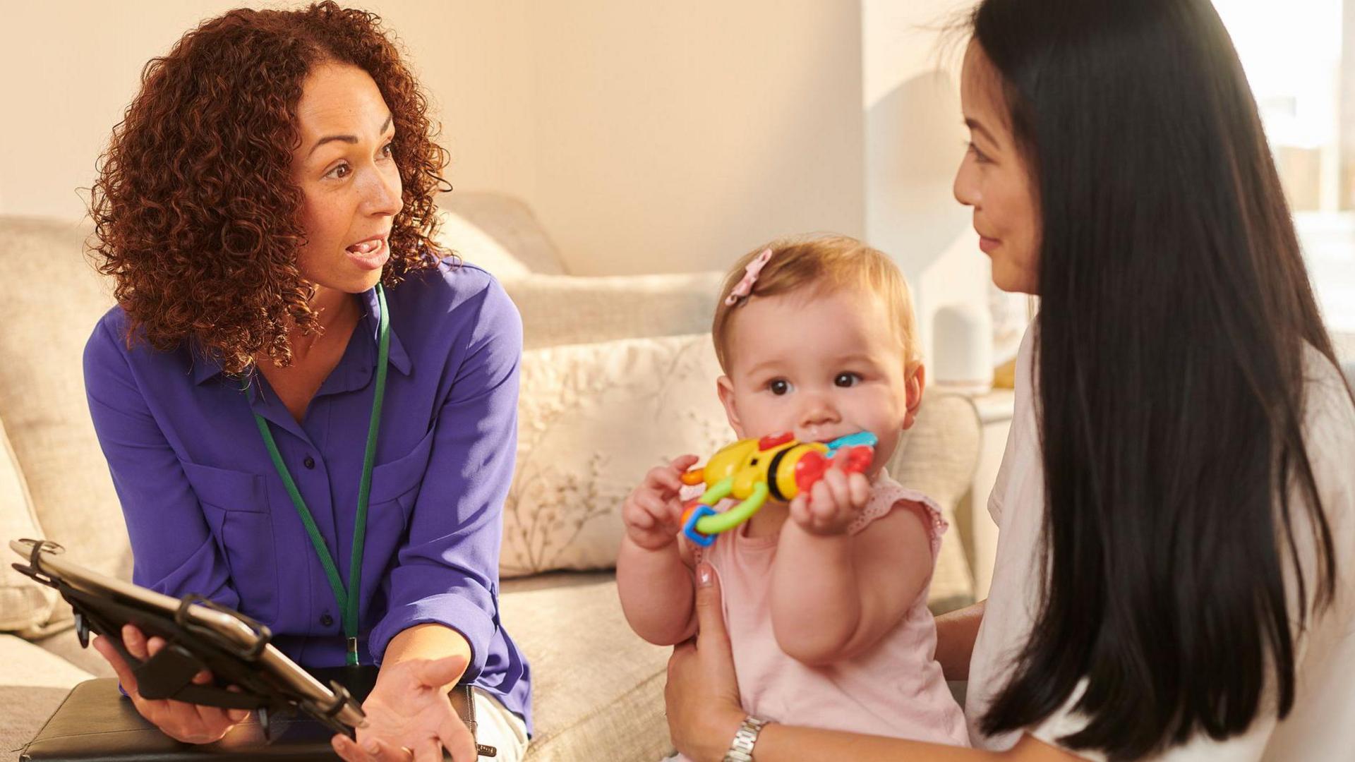 Llun ymwelydd iechyd gyda rhiant a phlentyn