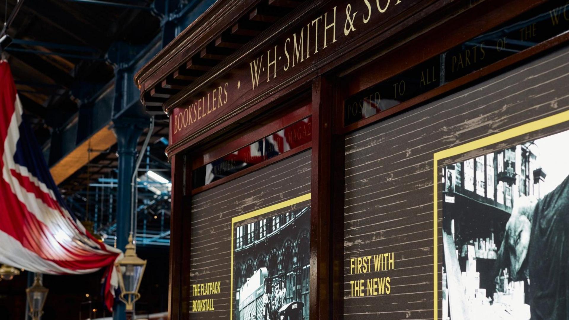 A wooden bookstall dating from 1921 with gold writing along the top stating WH SMITH & SON