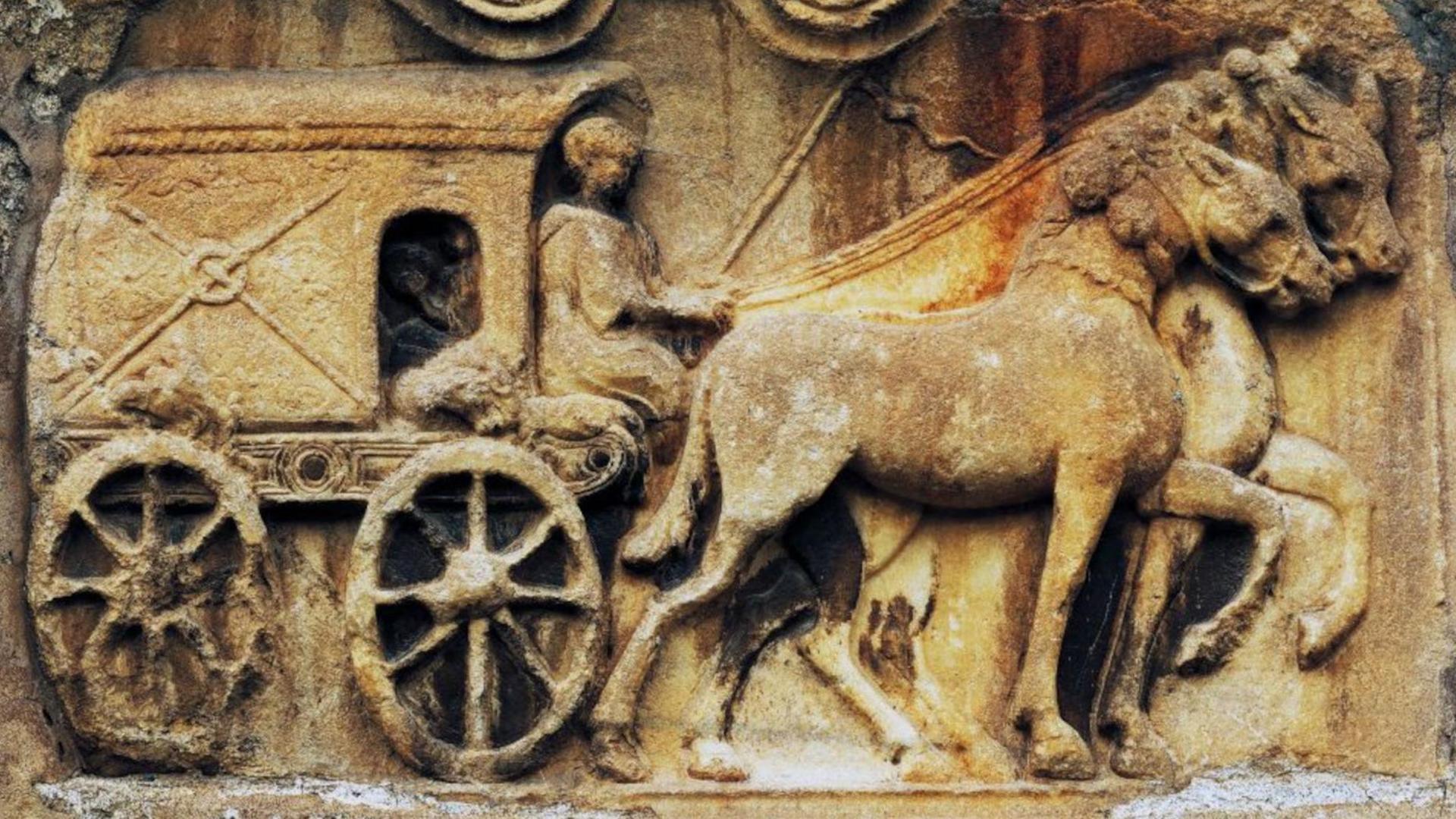 Roman relief depicting a carriage, Church of Maria Saal, Klagenfurt, Austria. Roman Civilisation, 1st to 2nd Century. The carriage is on the left, a covered vehicle with a window at its front, resting on two outside wheels. A driver is sitting at its front and it is being pulled by two horses.
