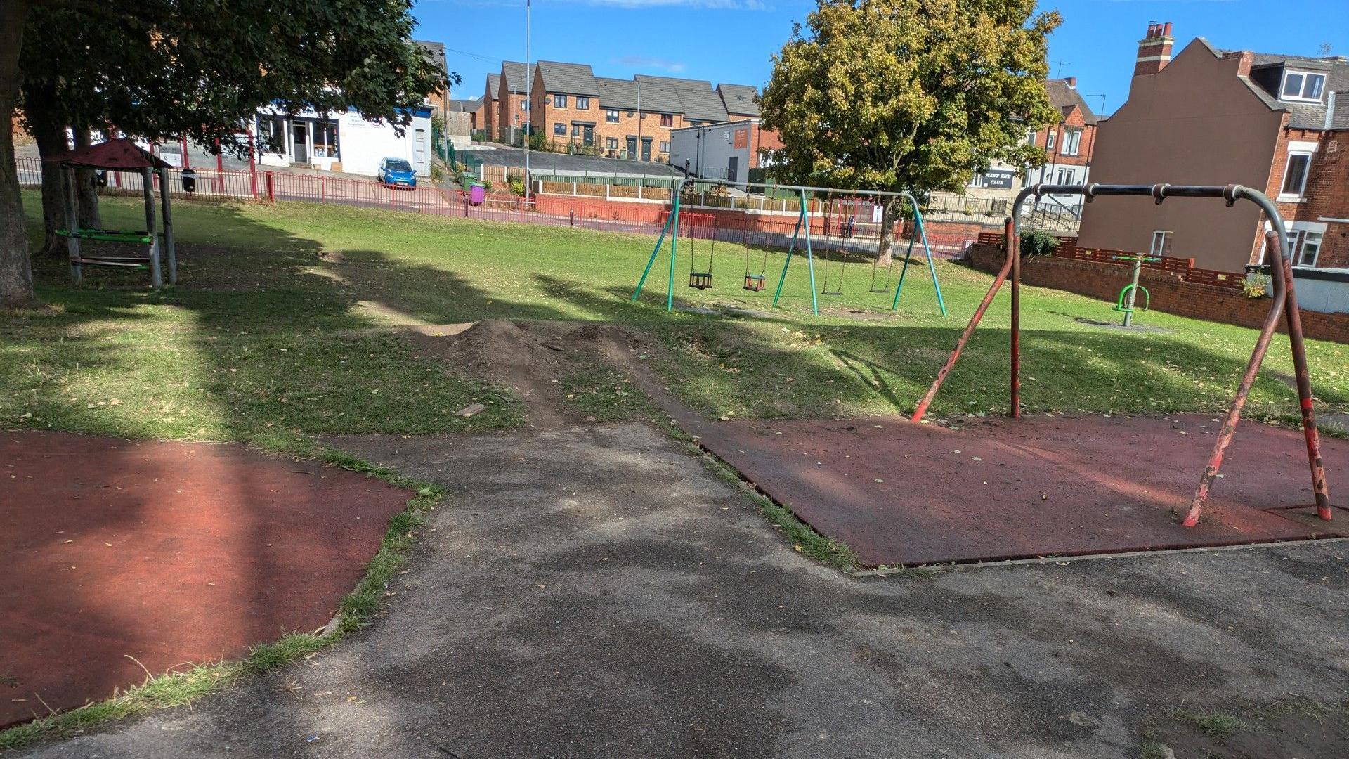 An empty playground in Hemsworth, West Yorkshire. Pictured in the foreground is a swing frame with chipped paint and without swings