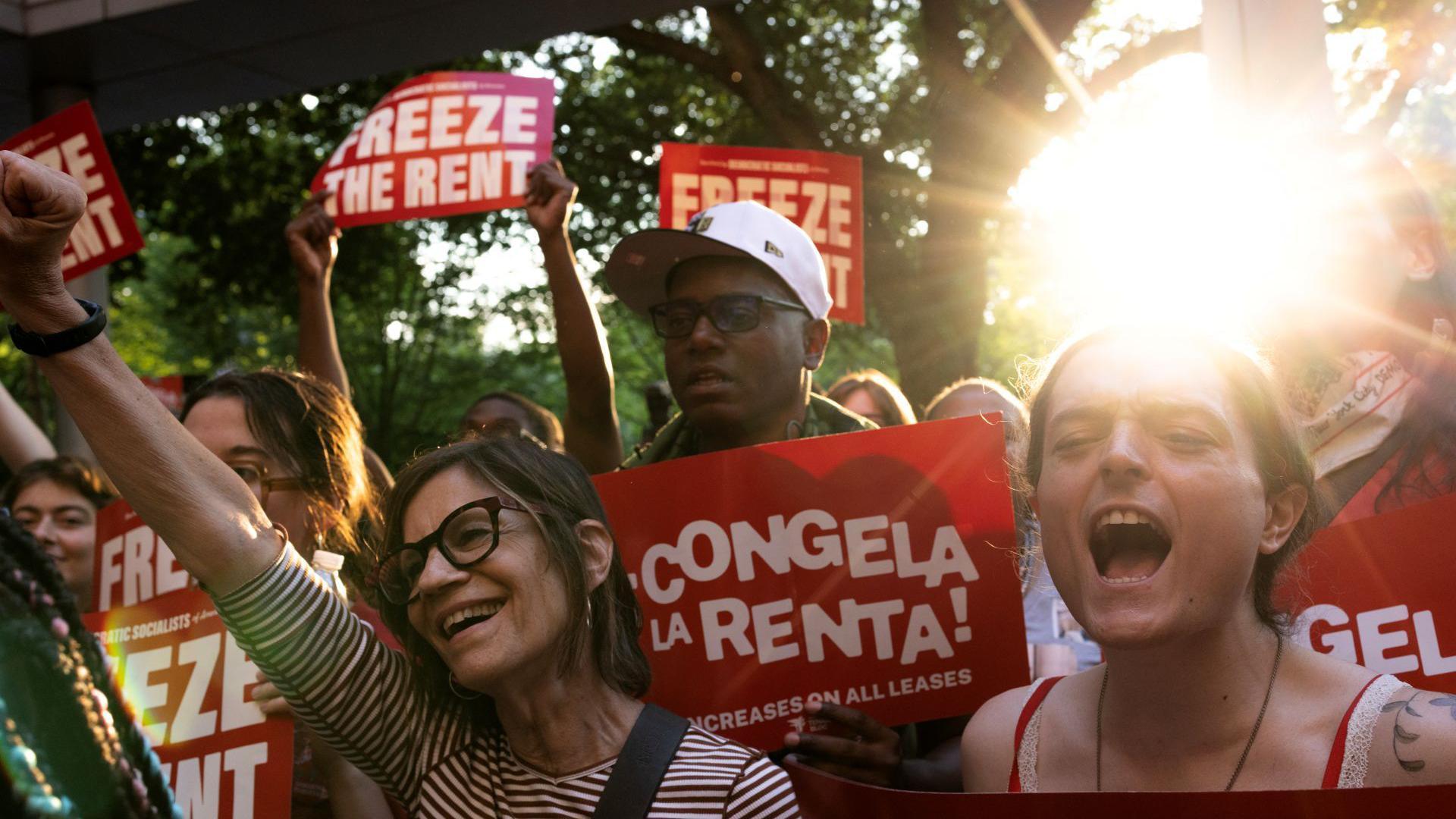 Tenant rights group members celebrating and cheering with sunshine and trees in the background in East Harlem, New York City.