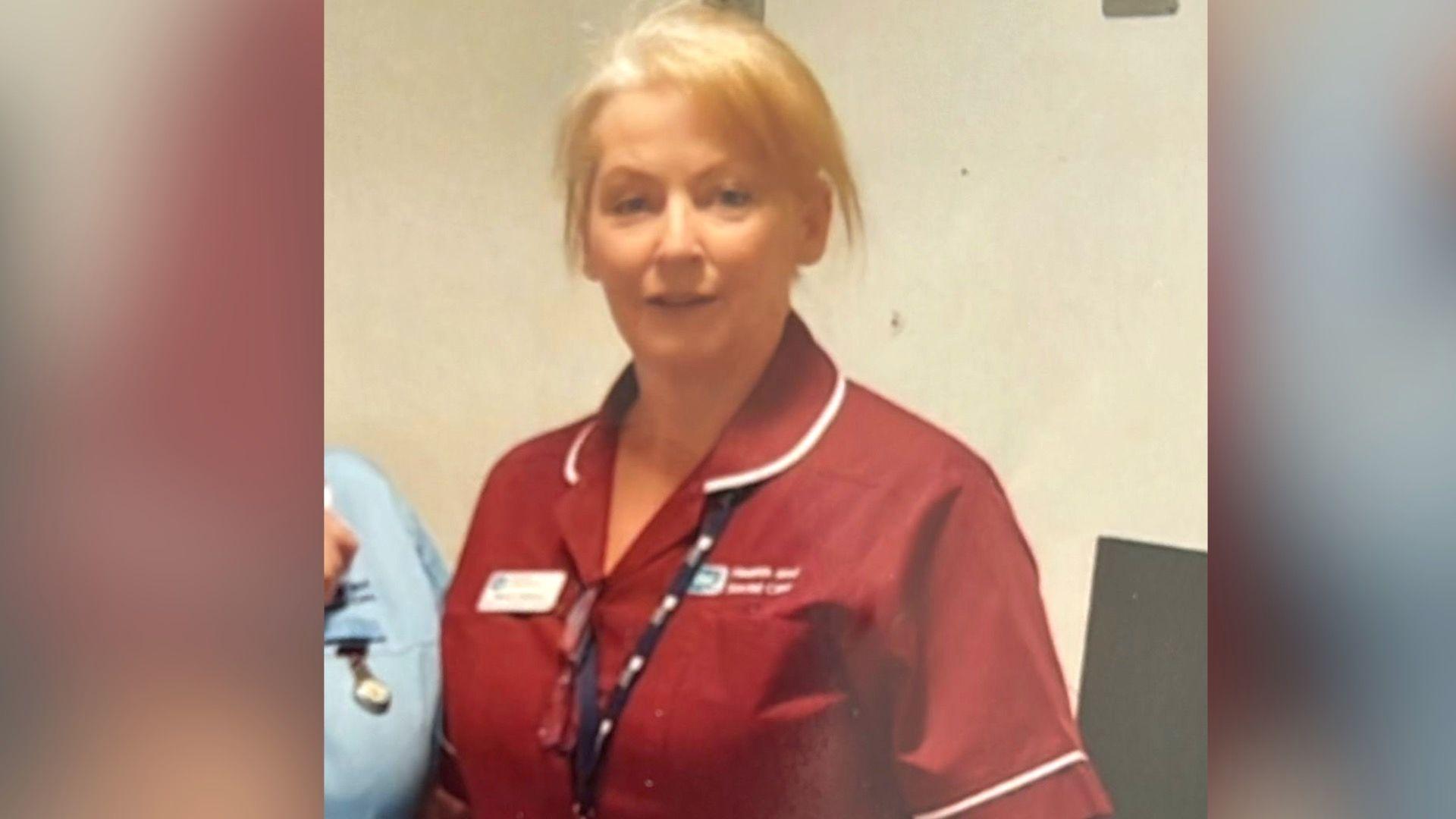 Monica Johnston in her red nurses uniform, she has short blonde hair.